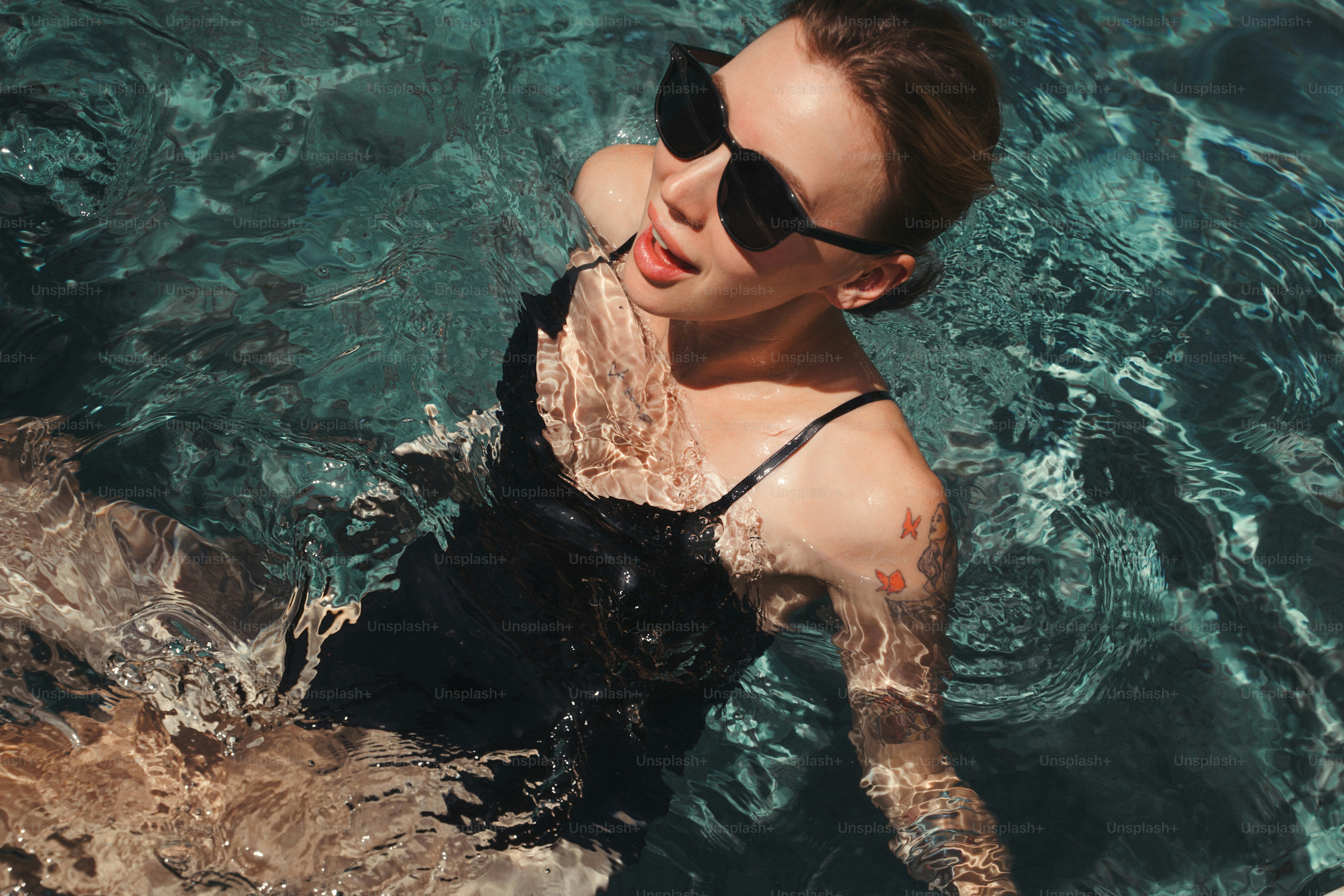 A woman in sunglasses swims in clear water.