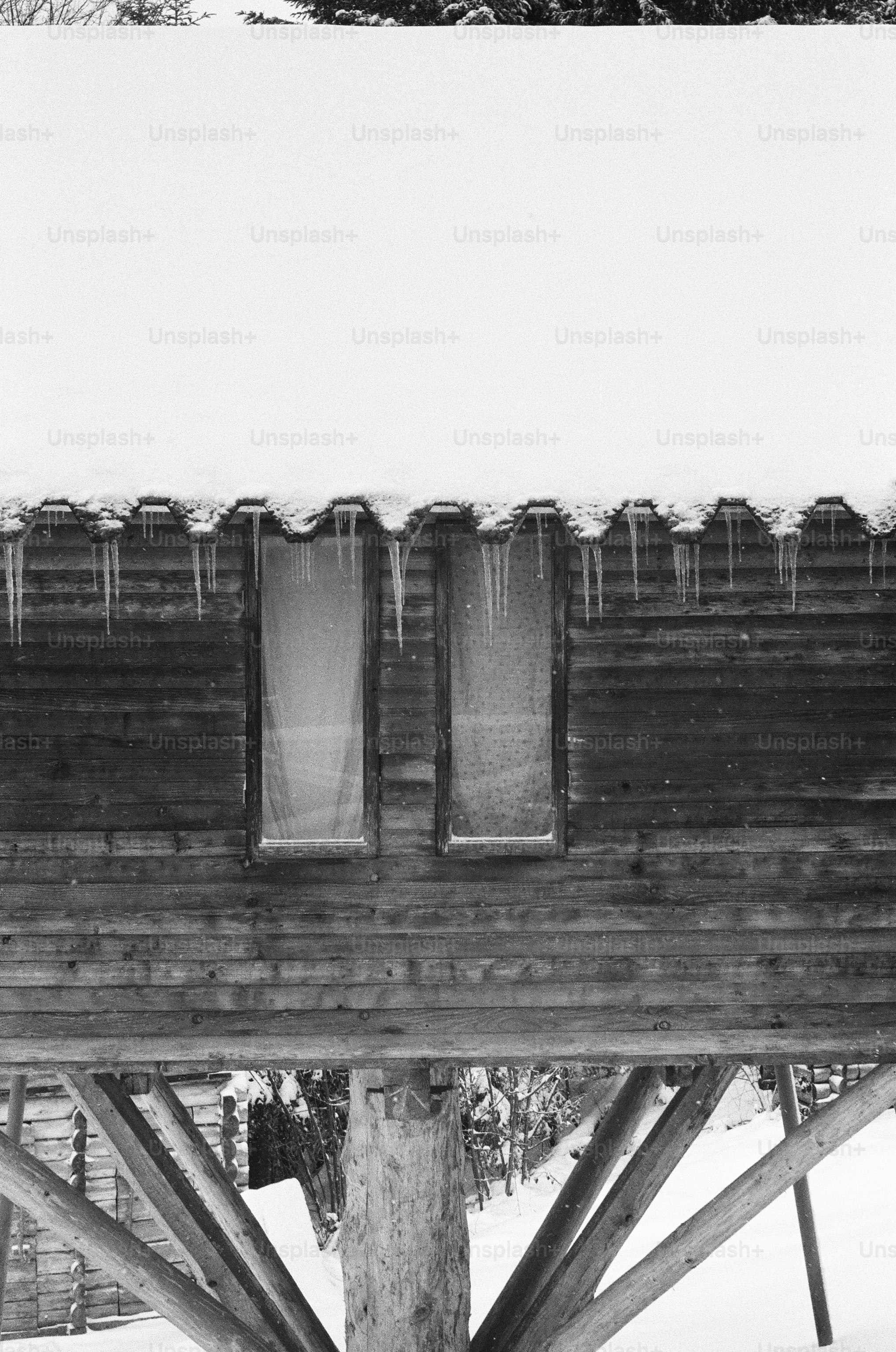 Holzhütte mit Eiszapfen auf schneebedecktem Dach
