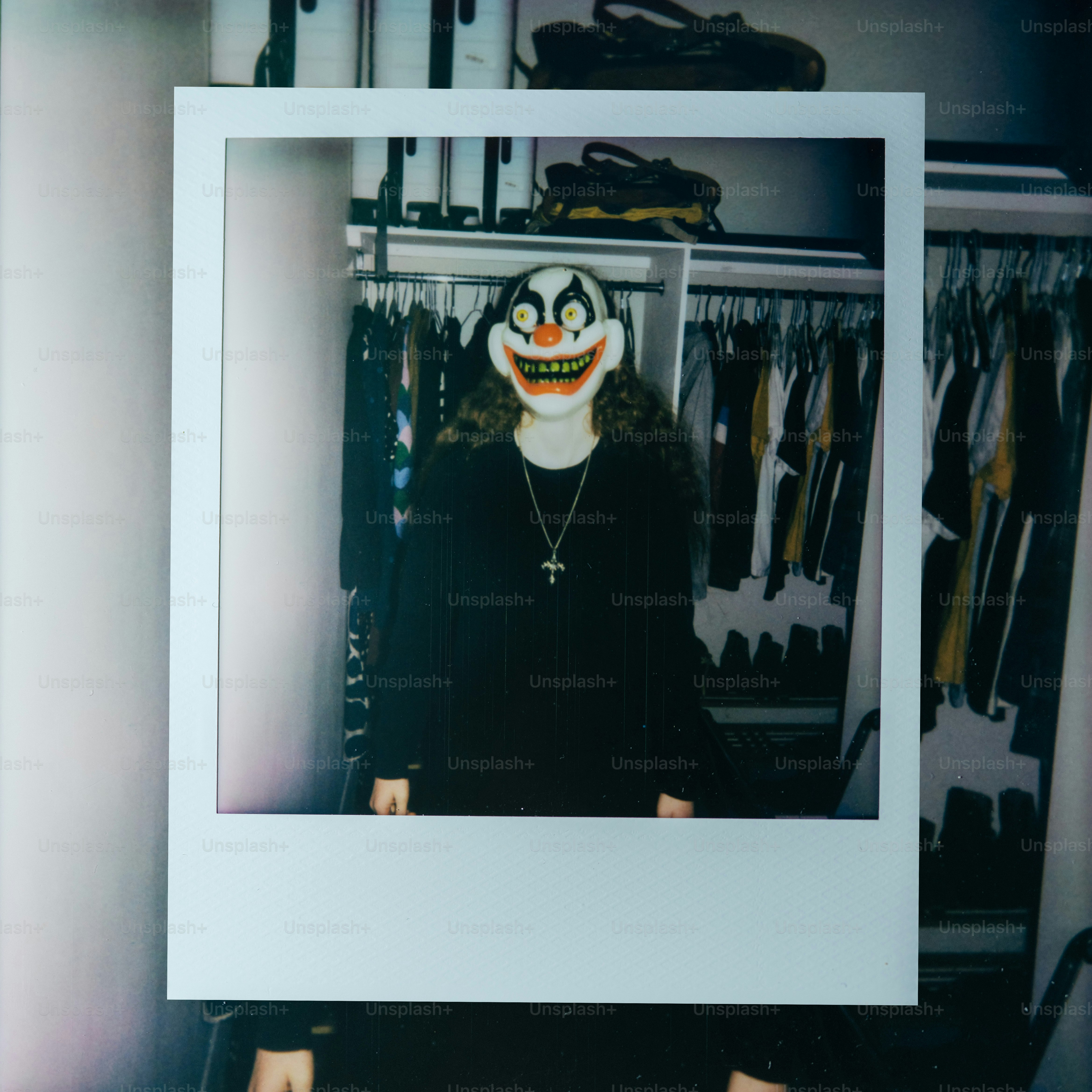 Person wearing a creepy clown mask in a closet