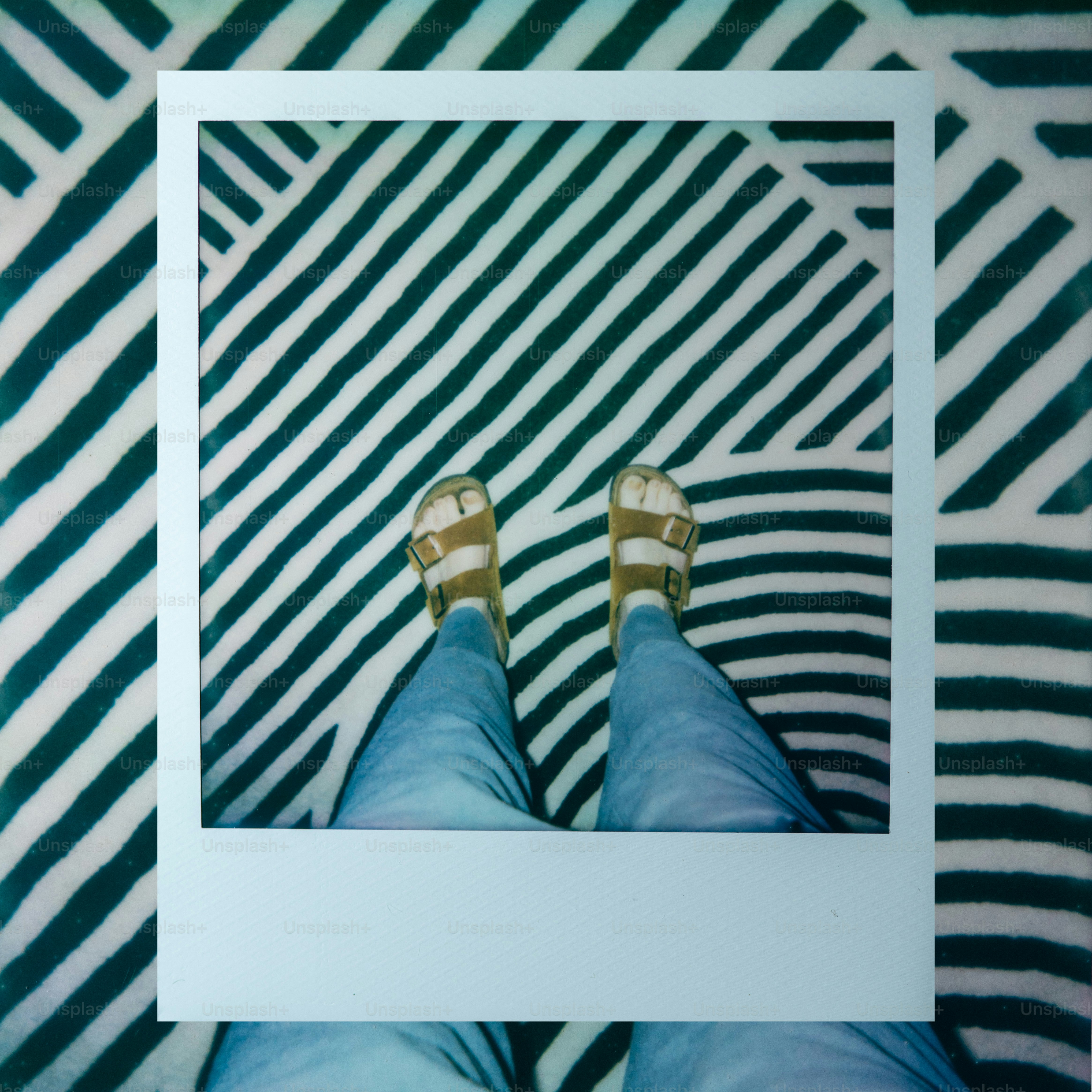 Feet in sandals framed by white border on striped background