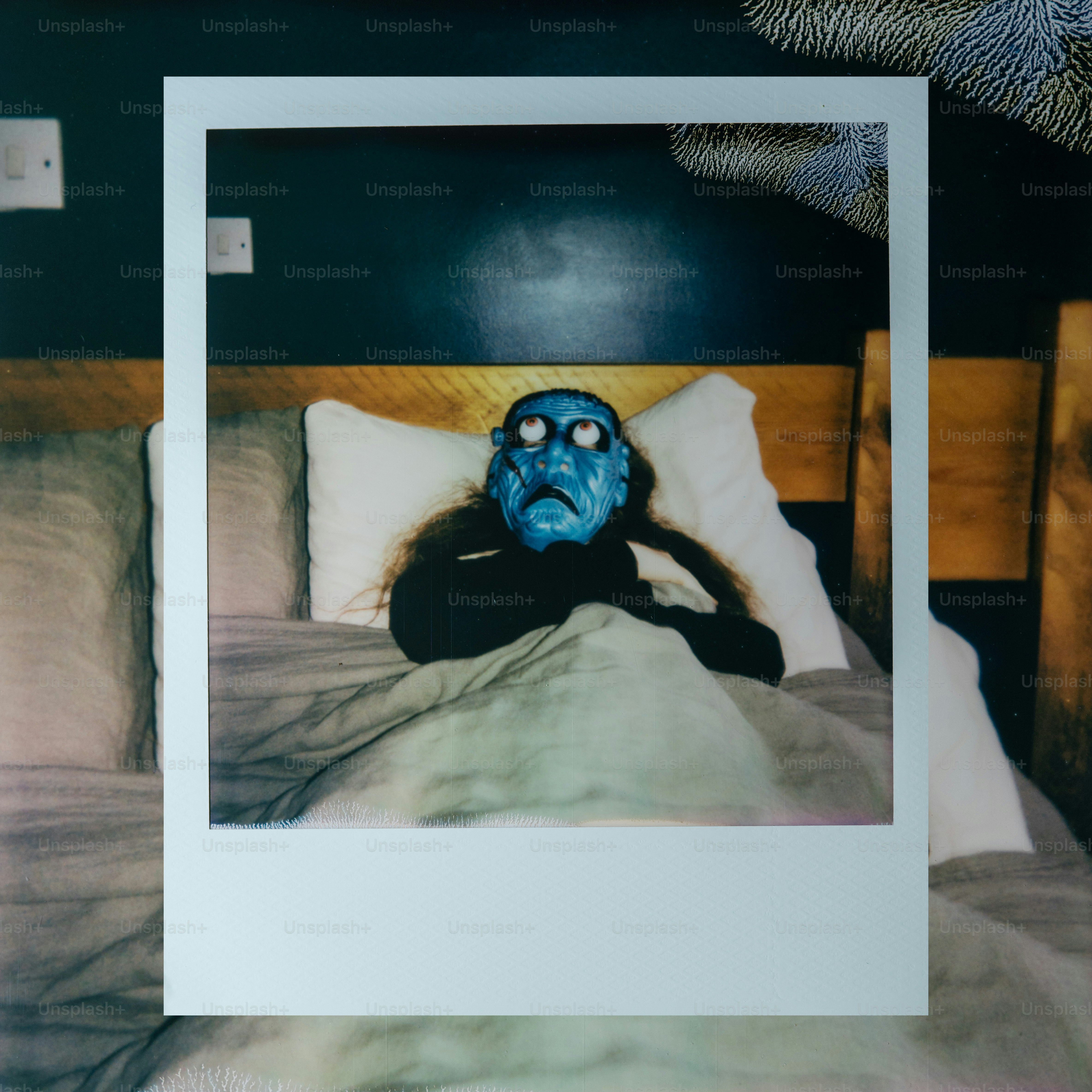 Blue masked figure lies in a bed
