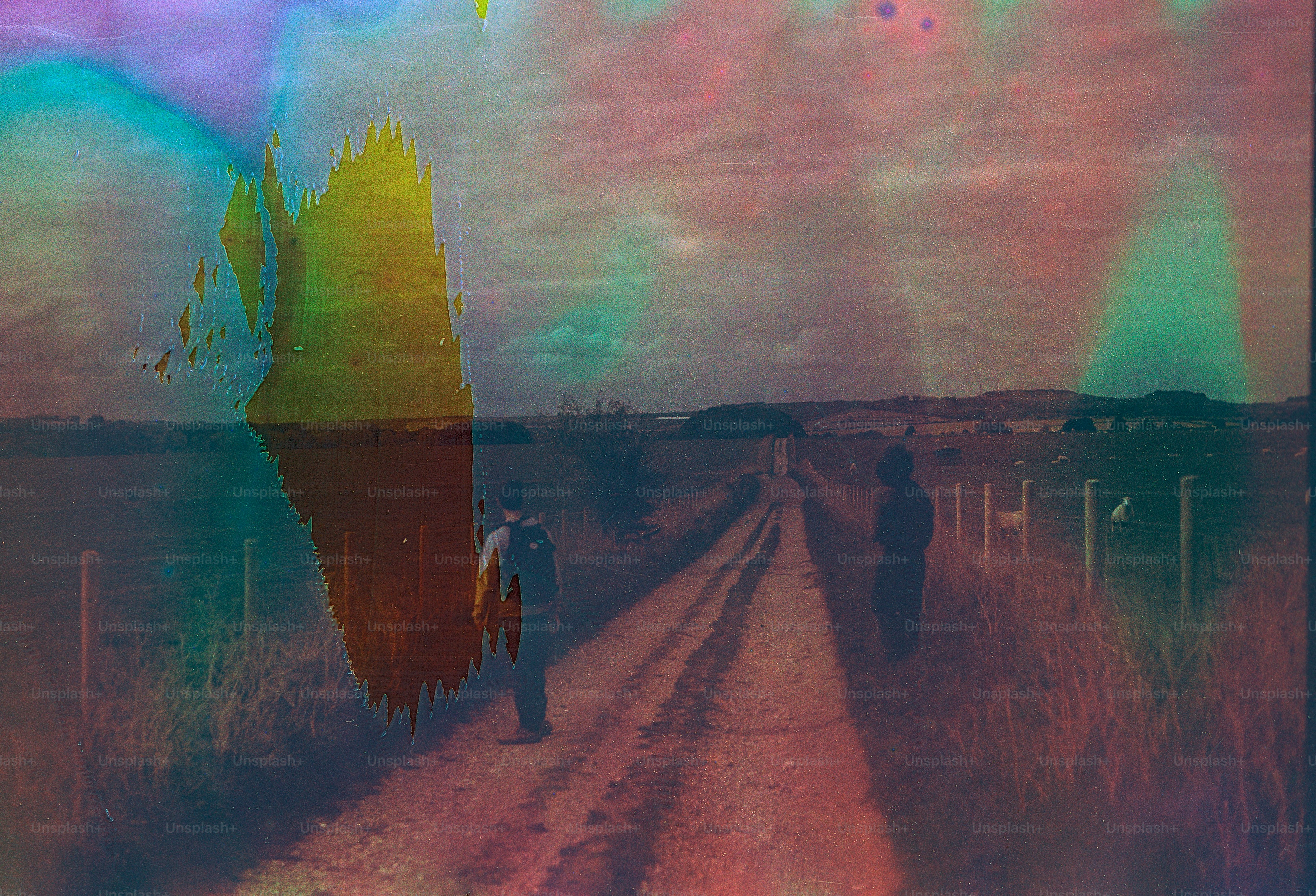 Two figures walk down a dirt road with colorful distortions.