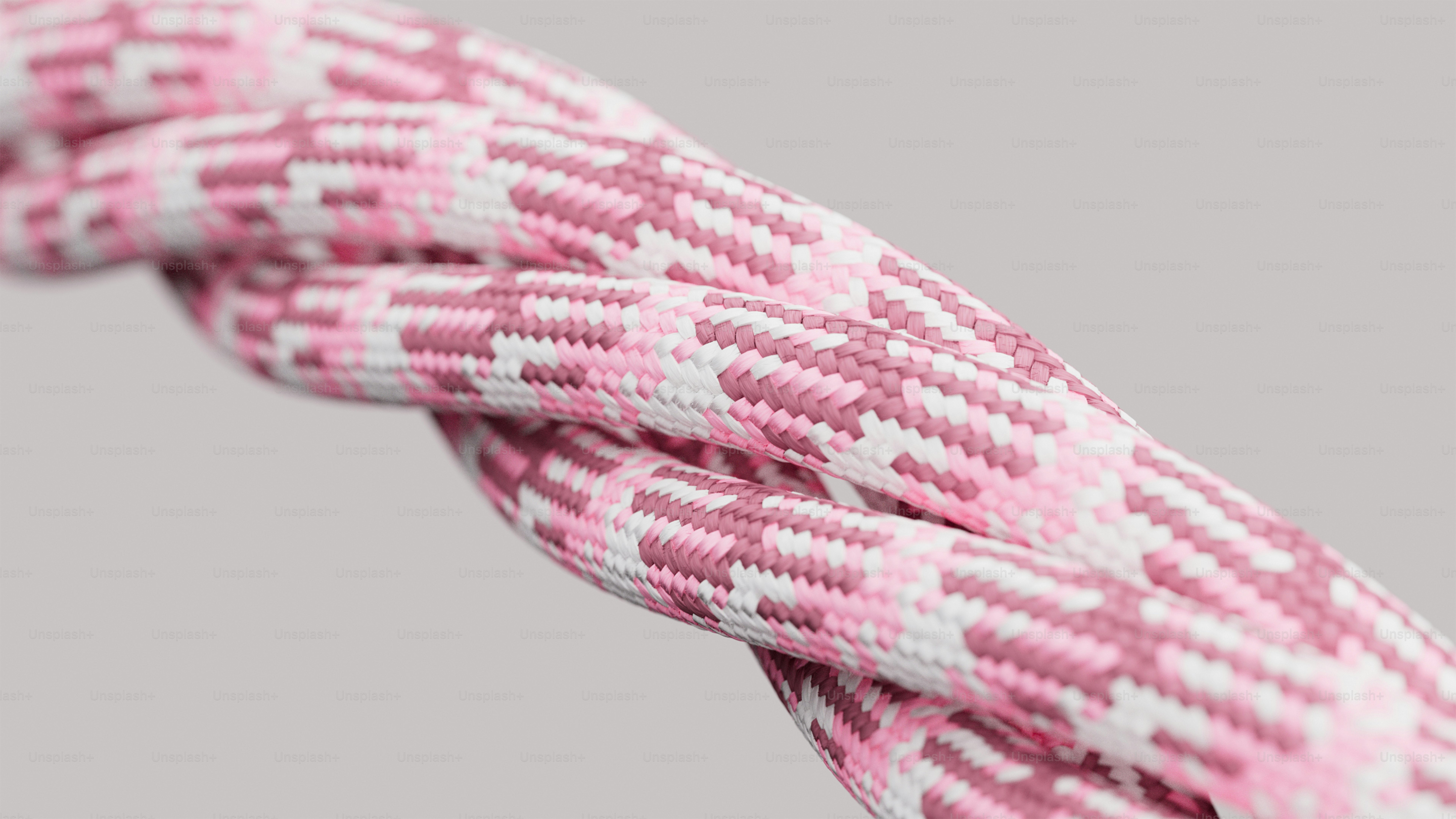 Close-up de duas cordas trançadas rosa e brancas entrelaçadas.