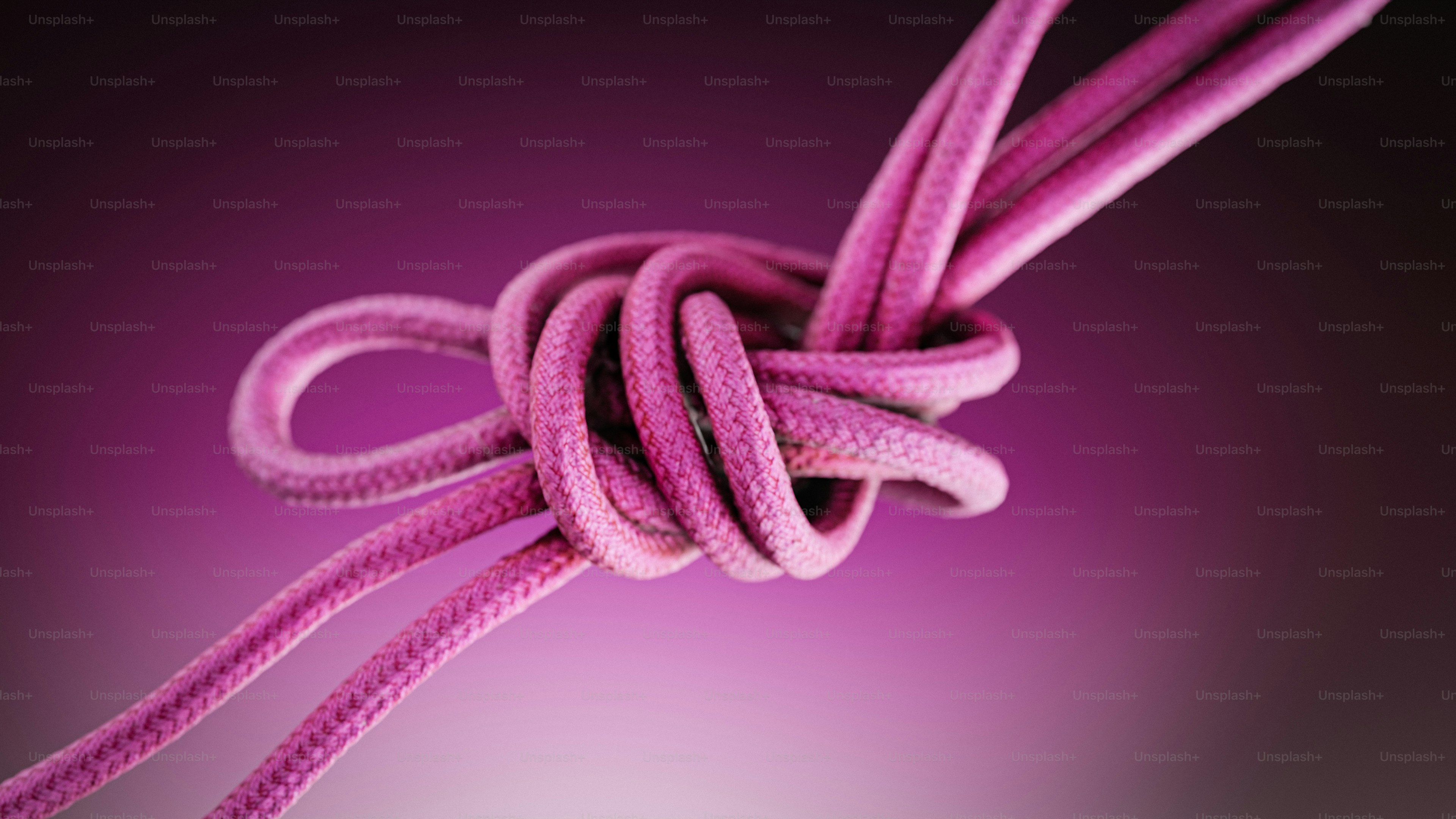 Um nó cor-de-rosa feito da corda em um fundo cor-de-rosa