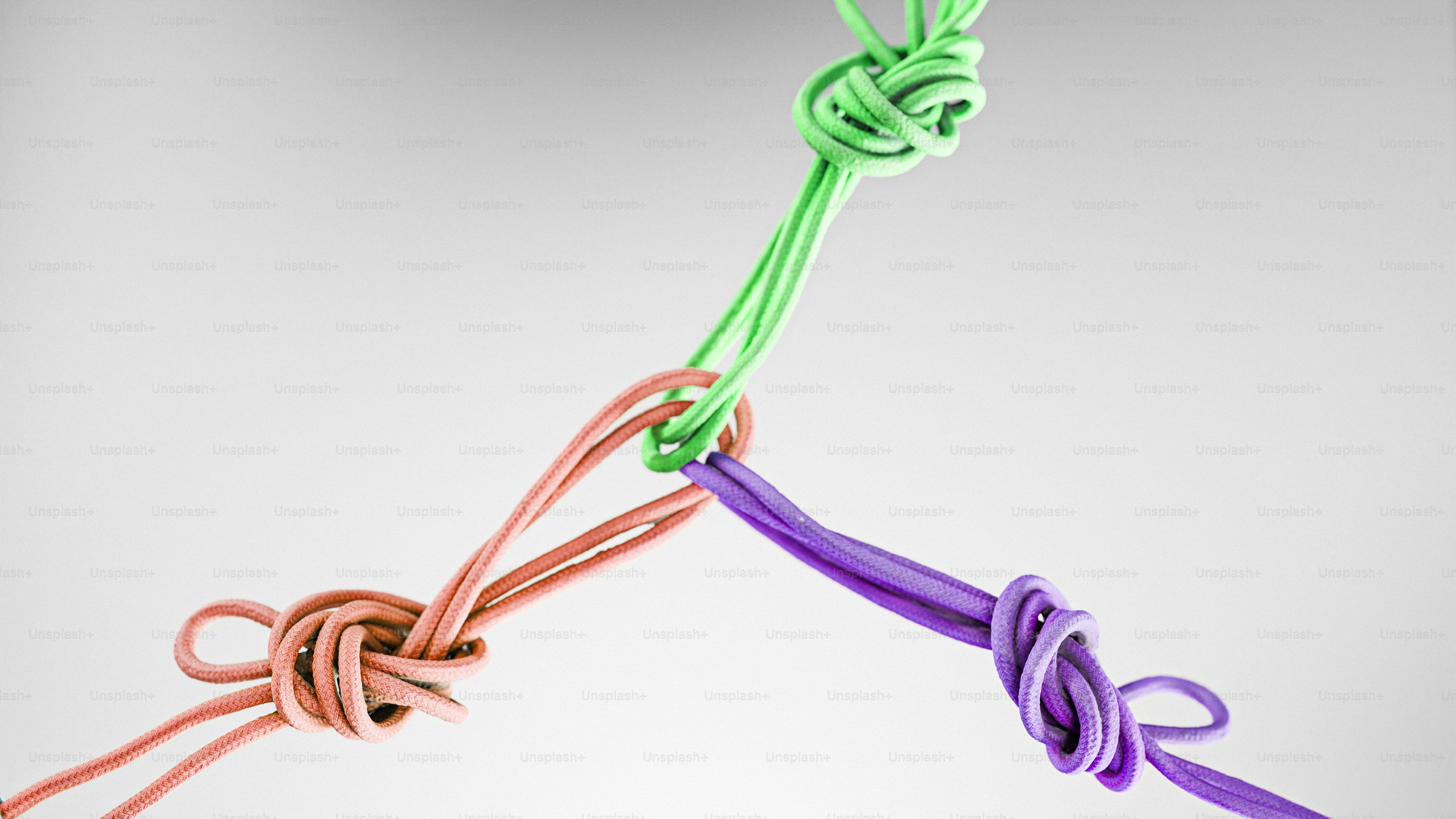 Three colorful ropes tied together in a knot.