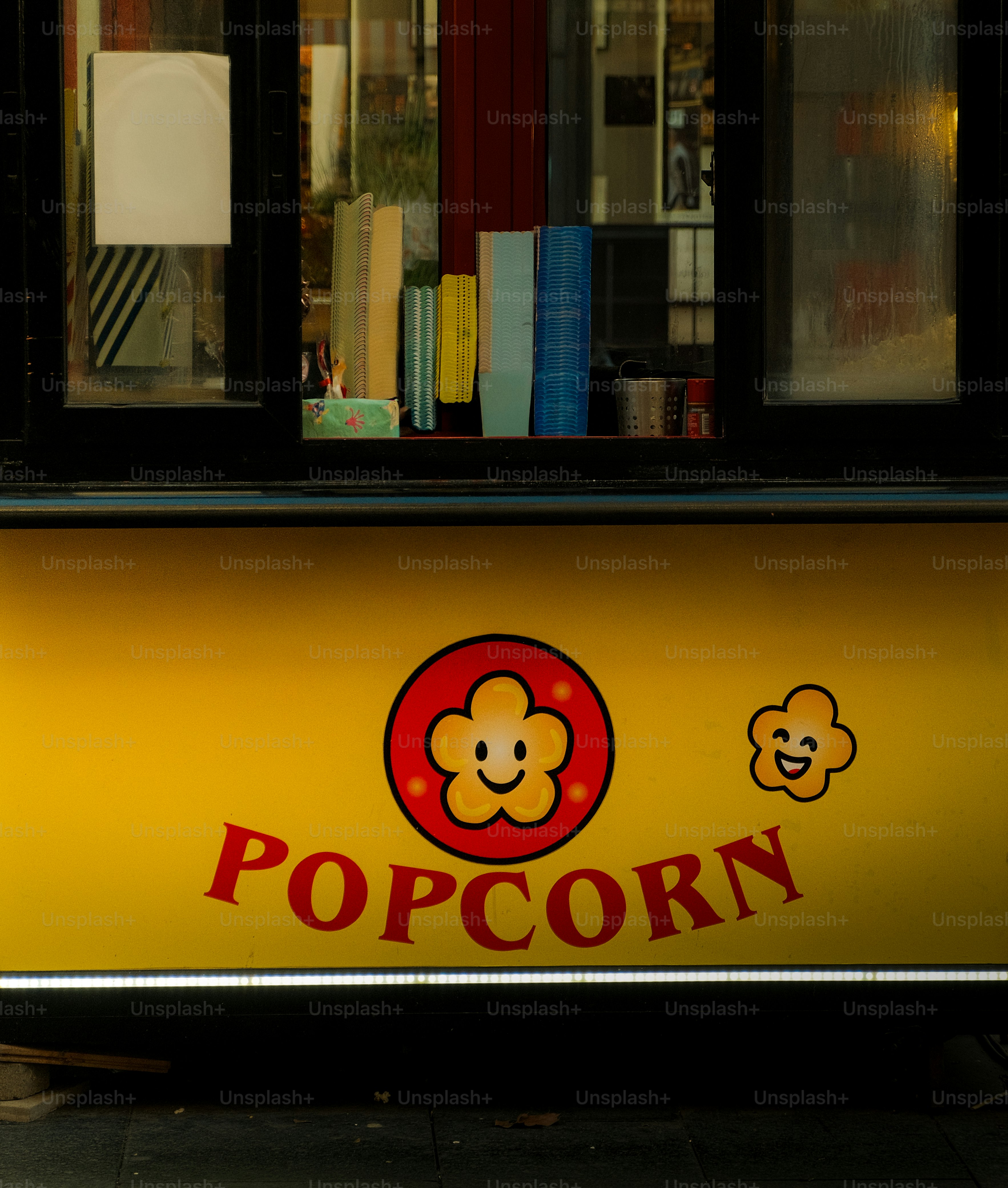 A yellow popcorn stand with cheerful mascot.
