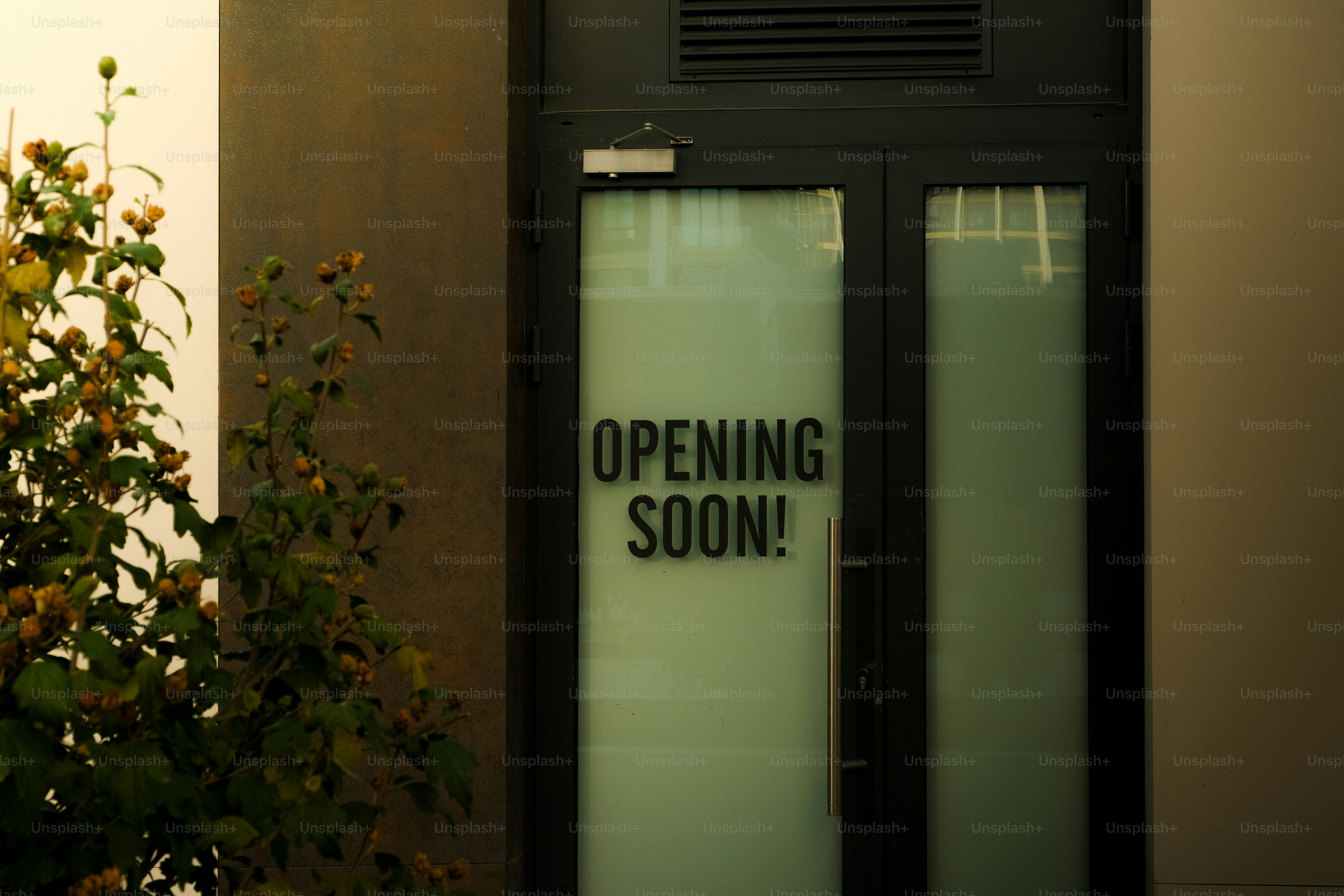 Glass doors with "opening soon!" sign.