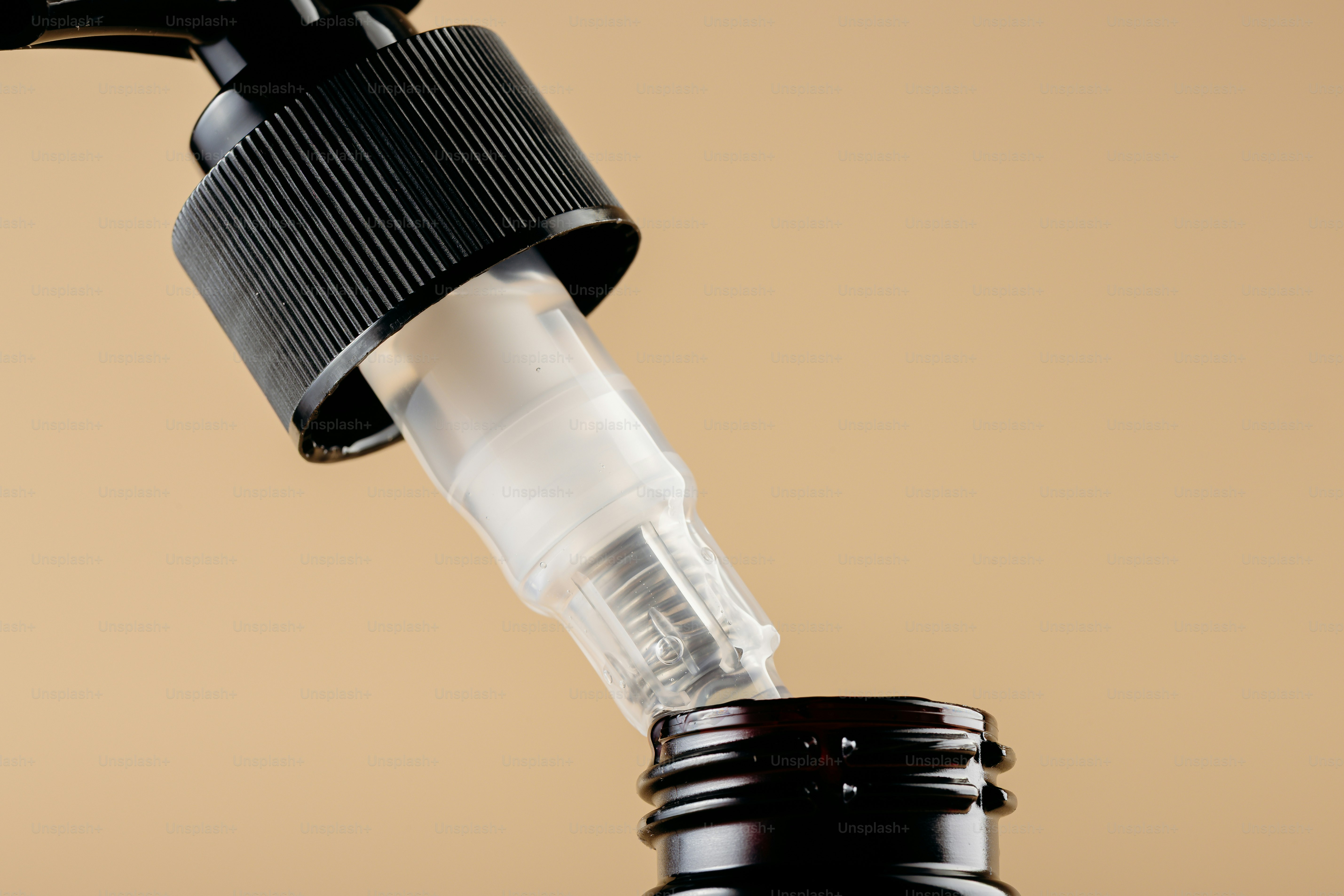 Black pump dispenser with clear tube over bottle