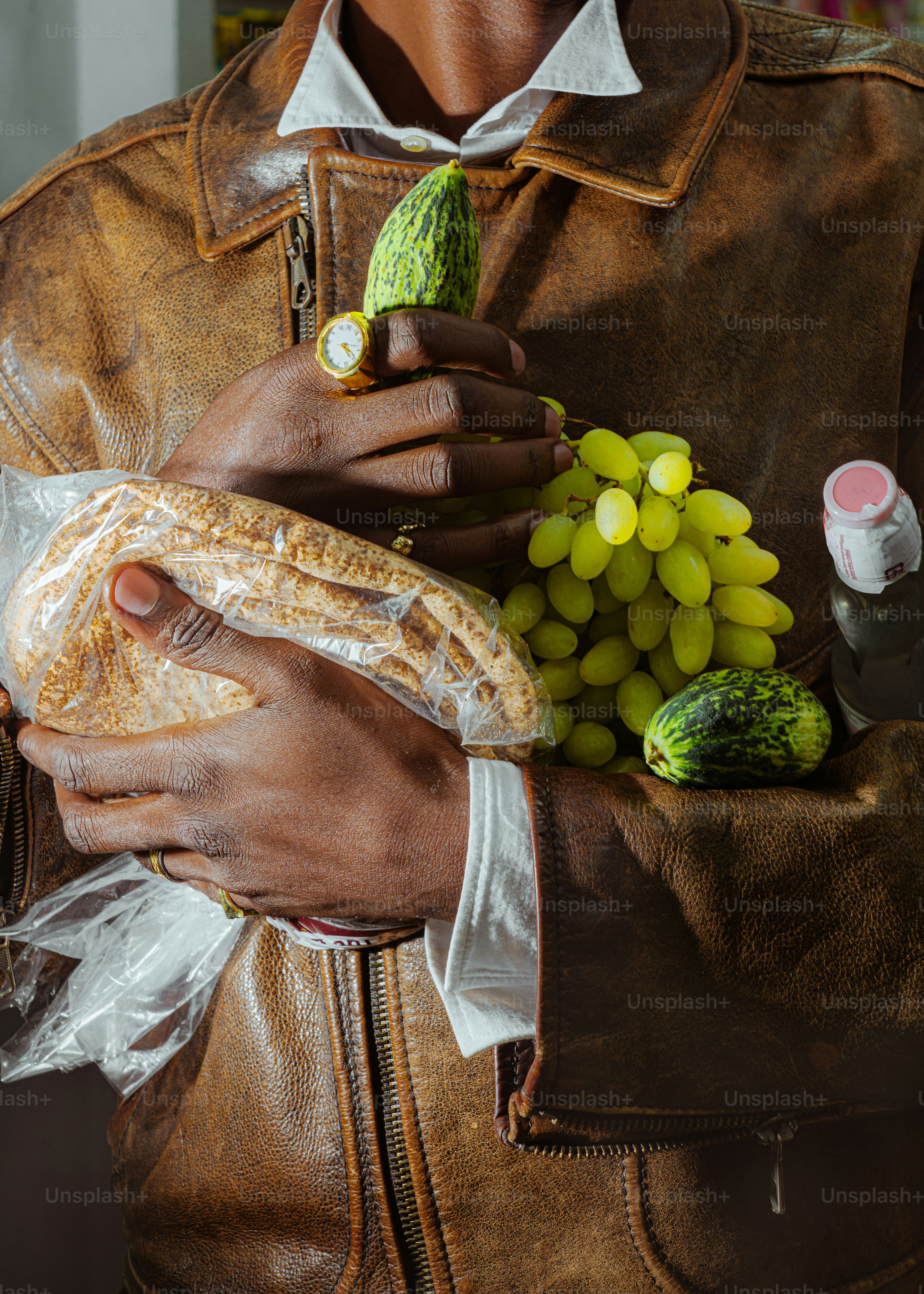 Person holding bread, grapes, and cucumbers