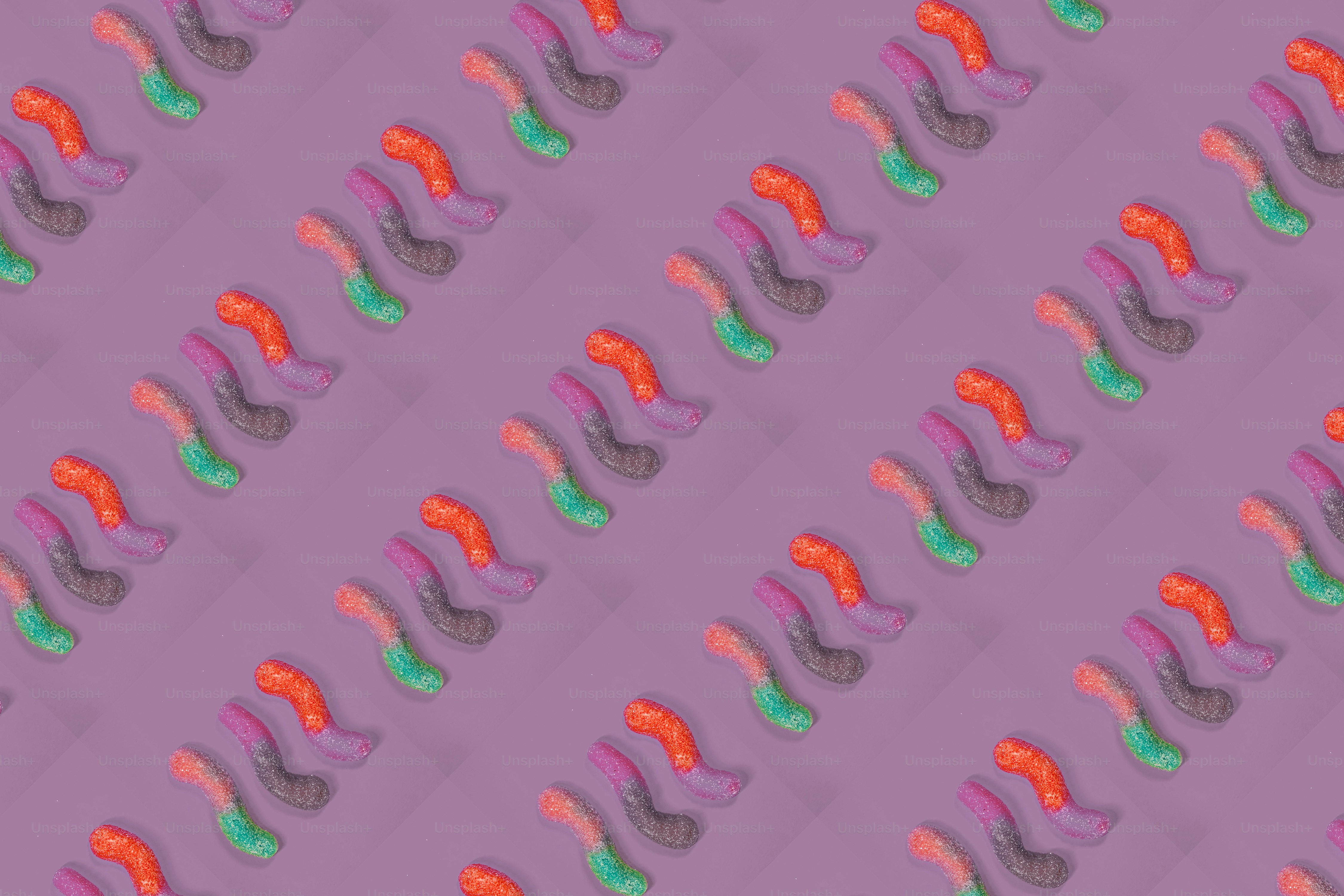 Rows of colorful gummy worms on purple background