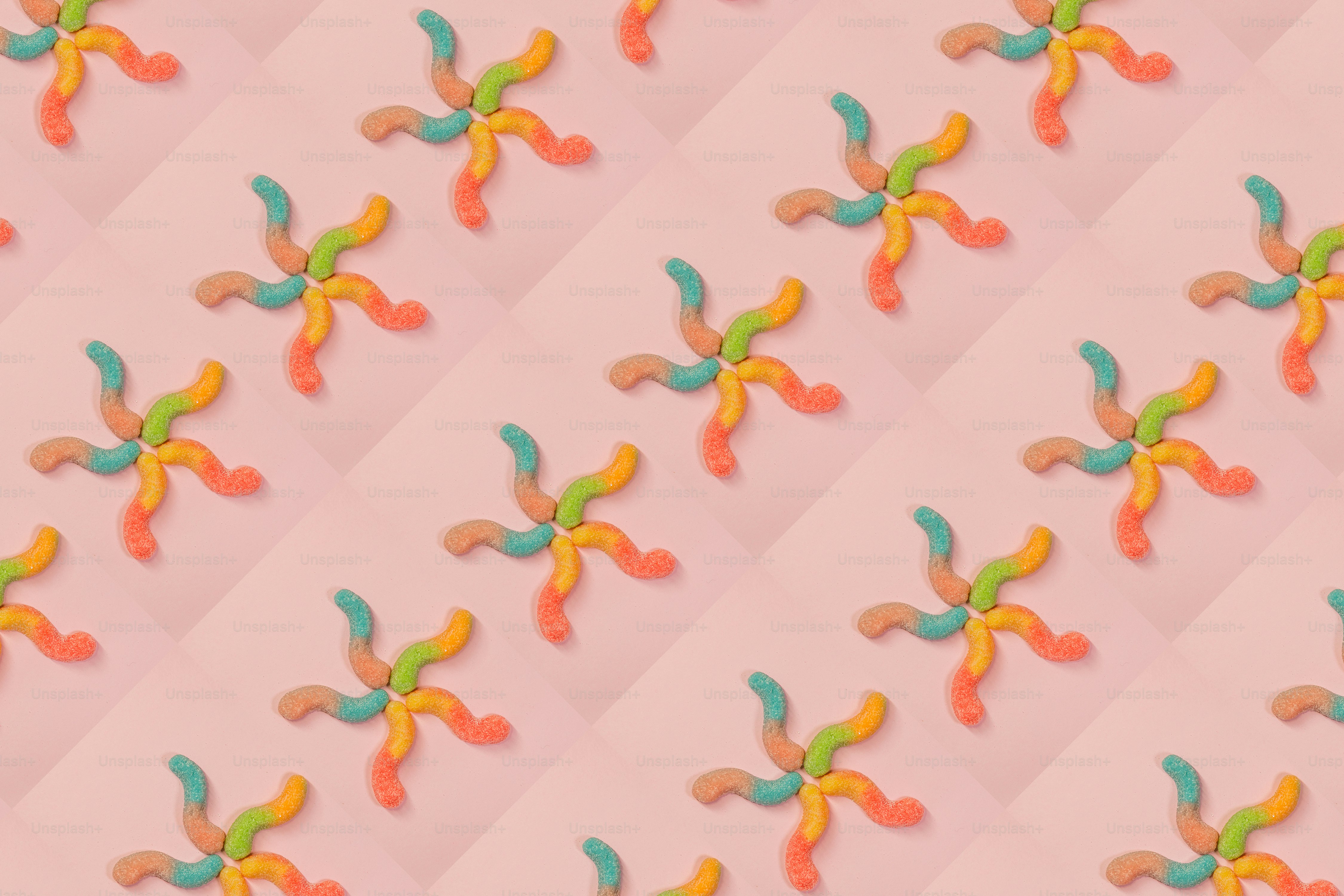 Gummy worms arranged in star shapes on pink background