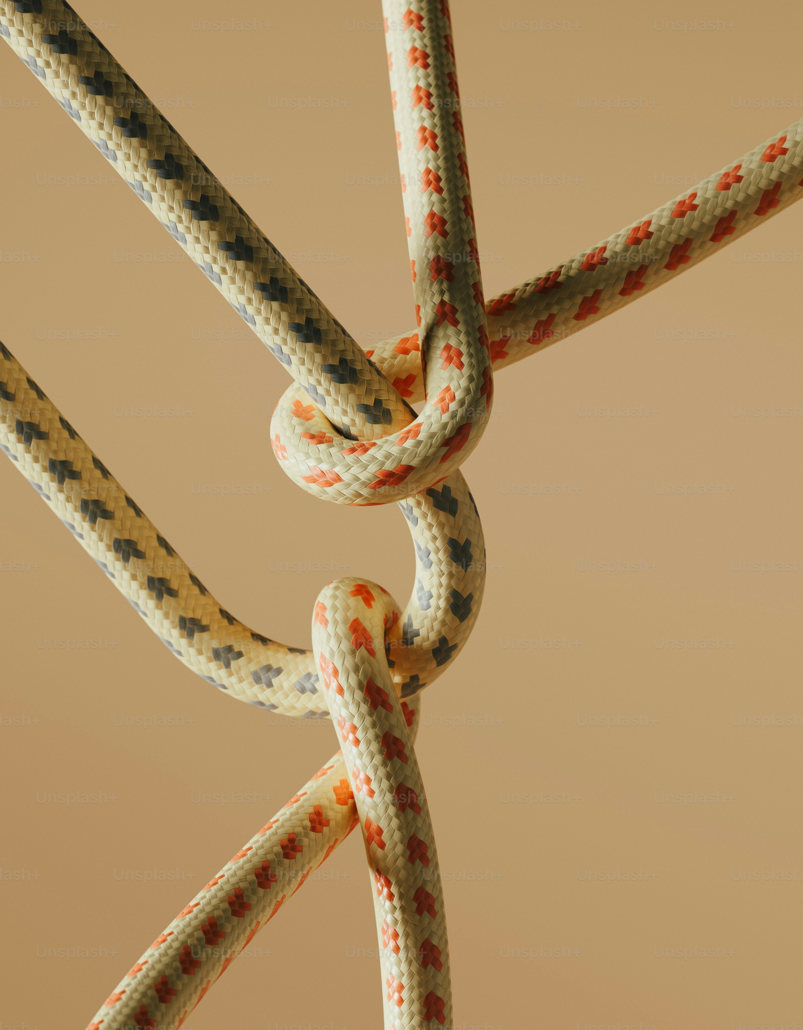 Intertwined ropes form a knot against a plain background.