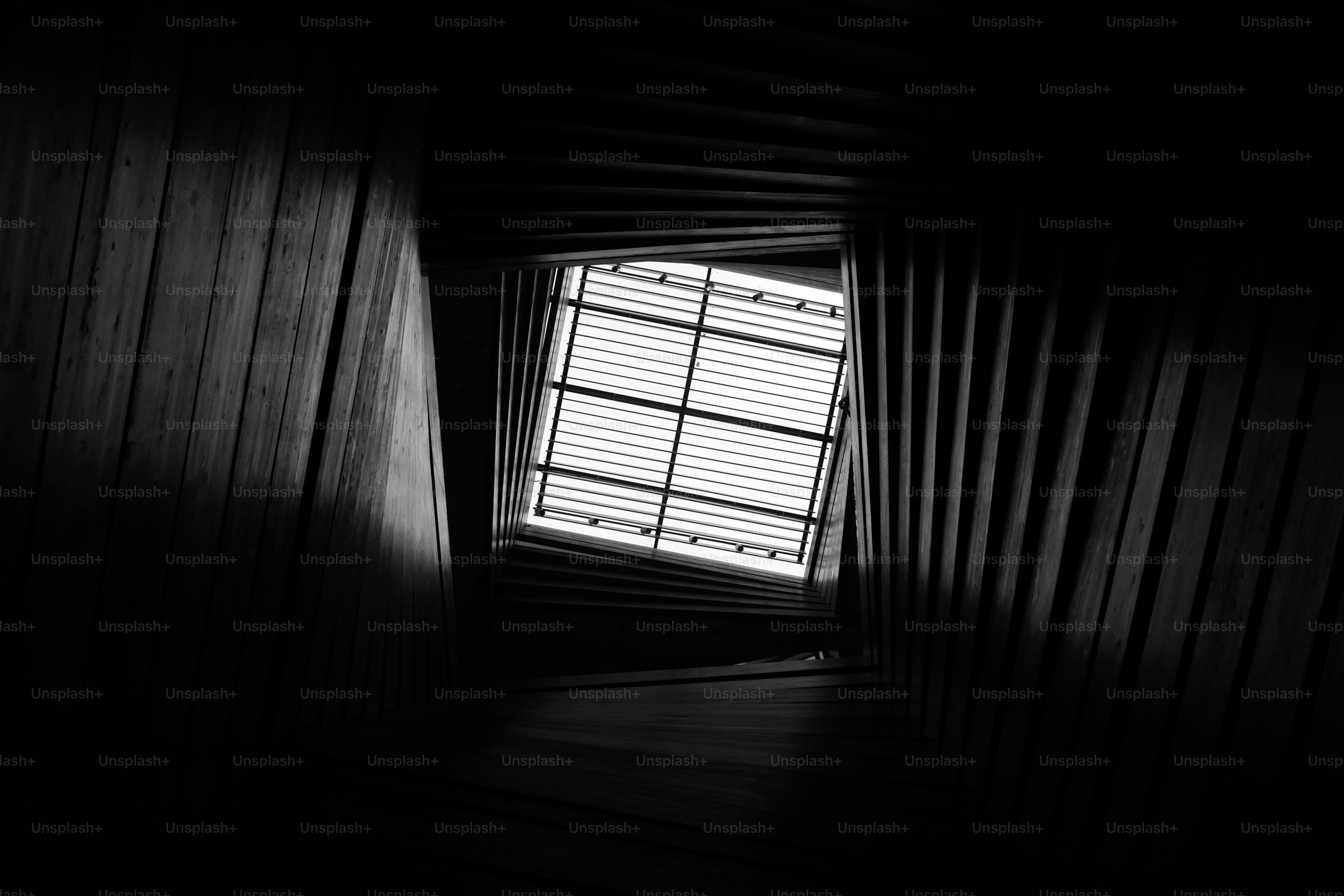 Looking up through a dark stairwell towards skylight.