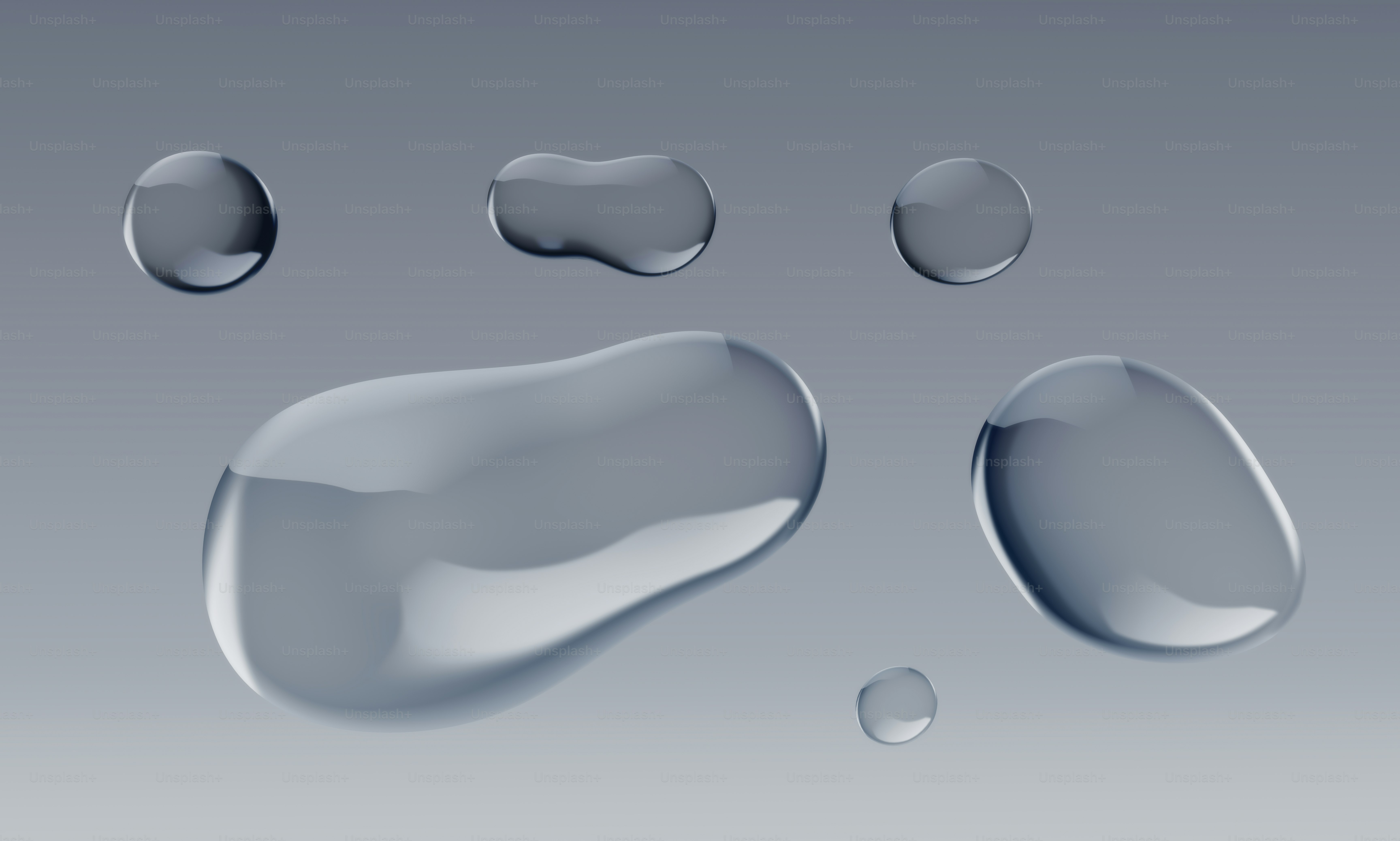 Several clear water droplets on a gray surface.
