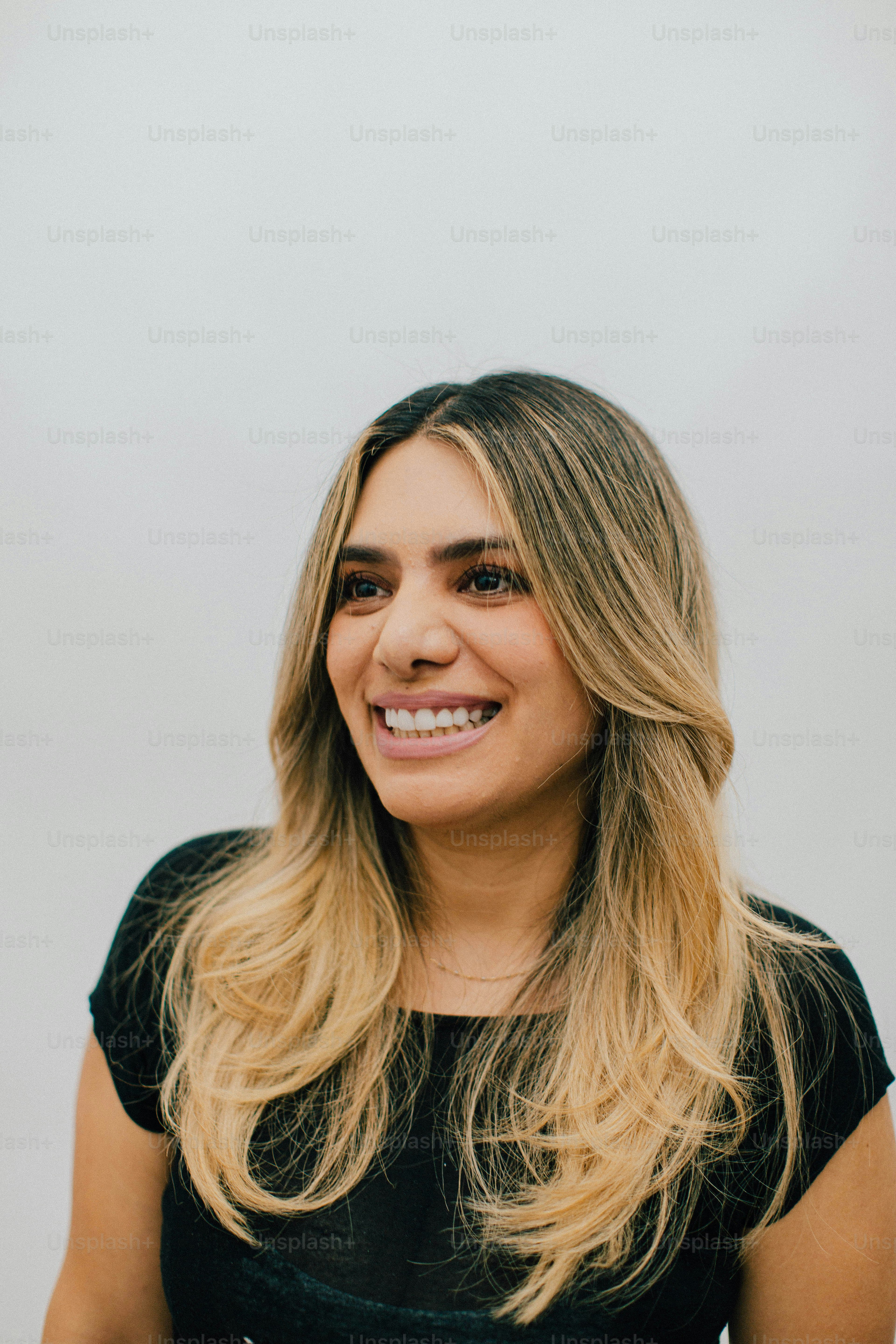 Una mujer sonriente con cabello rubio sobre un fondo blanco