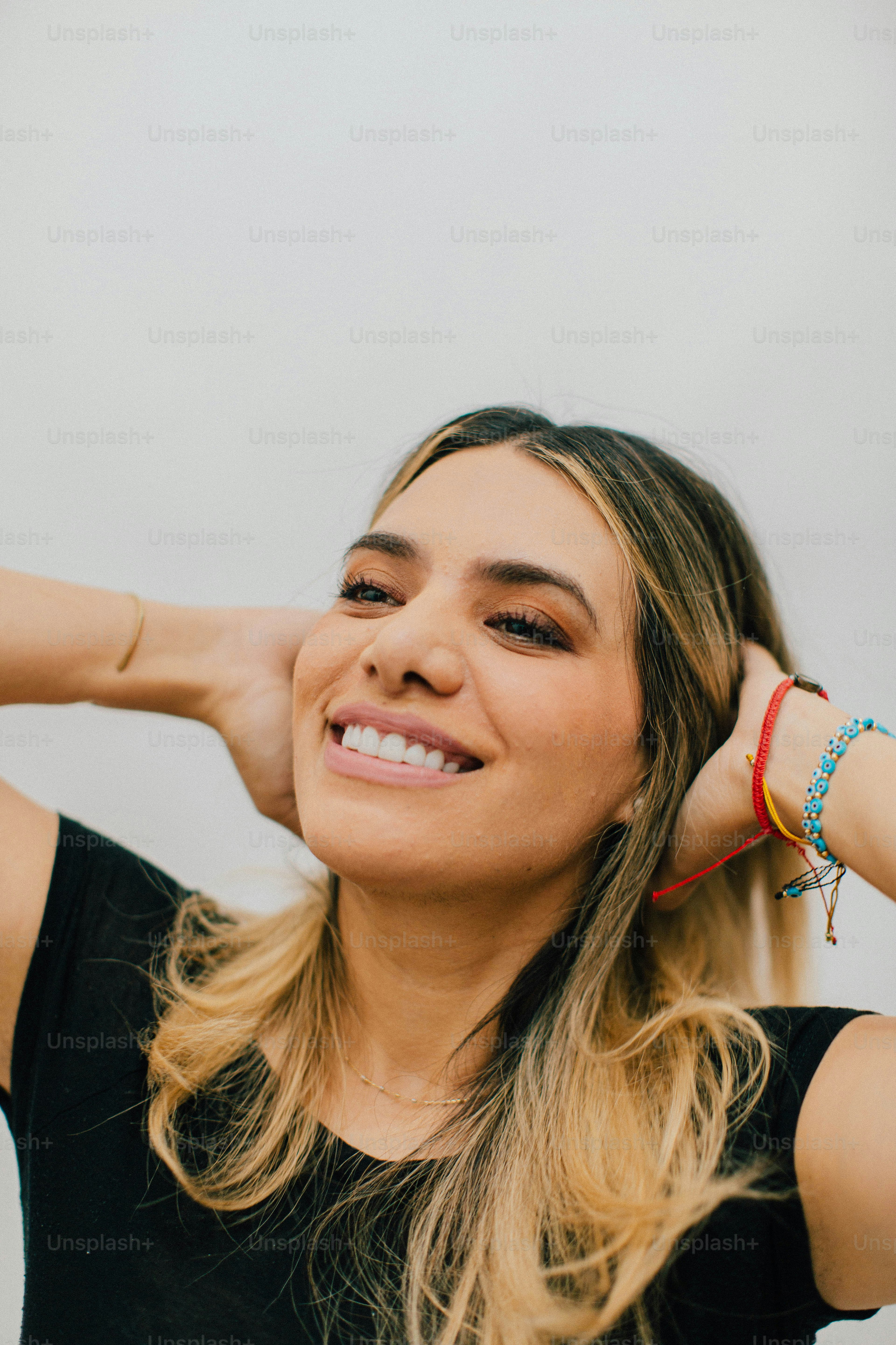 Una mujer con las manos detrás de la cabeza sonriendo