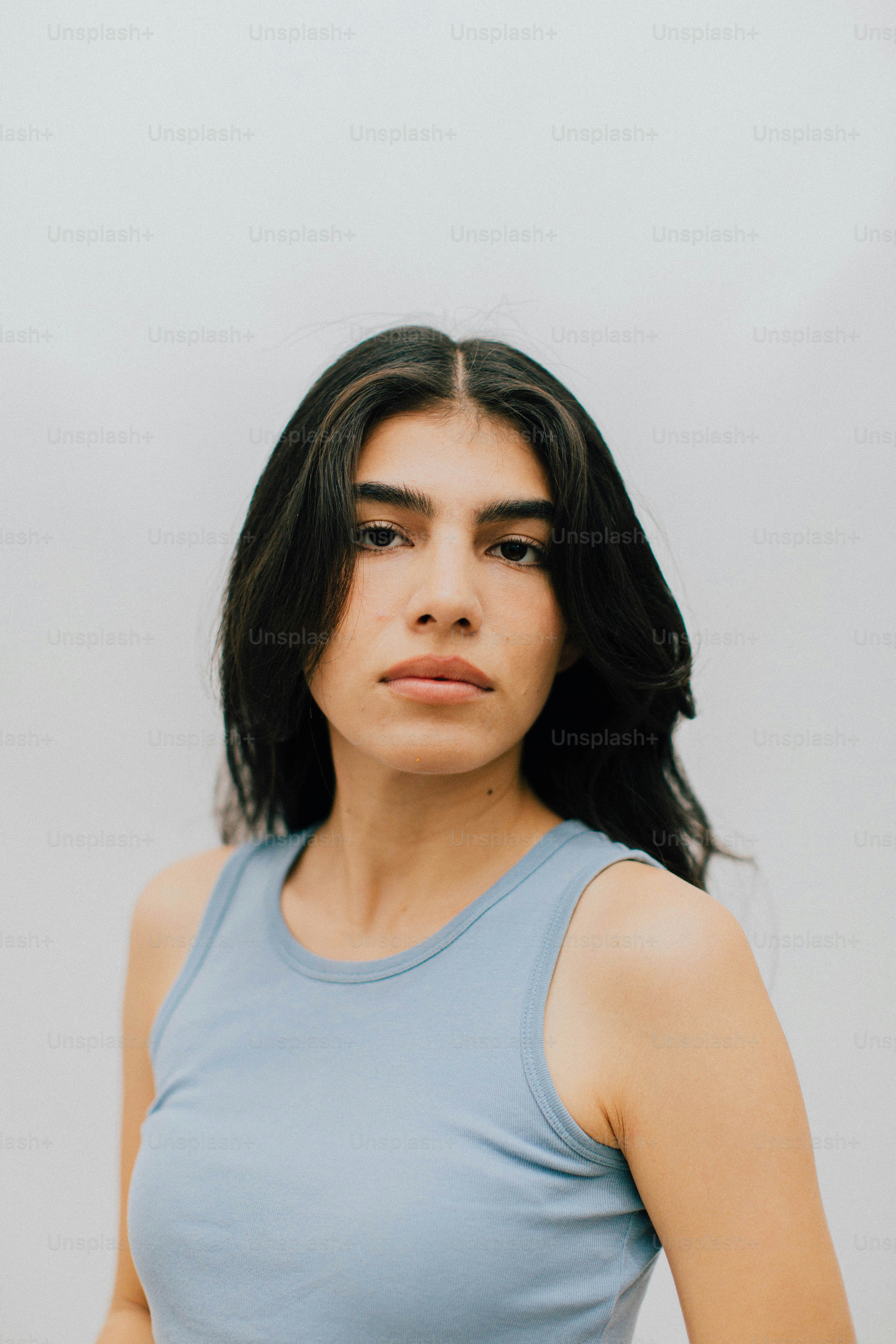 Giovane donna con i capelli scuri che indossa una canotta blu.