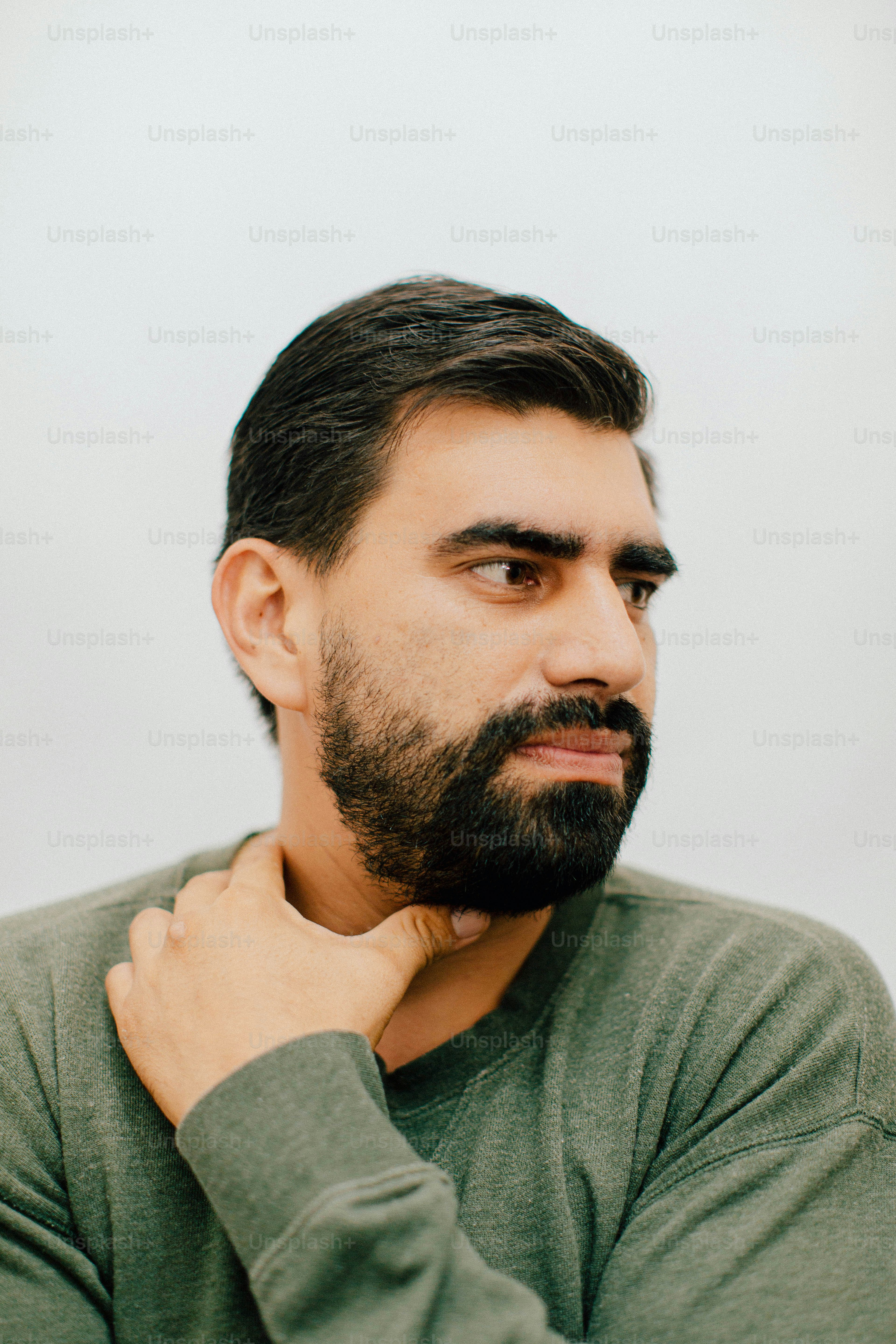 Hombre sosteniendo su cuello con barba