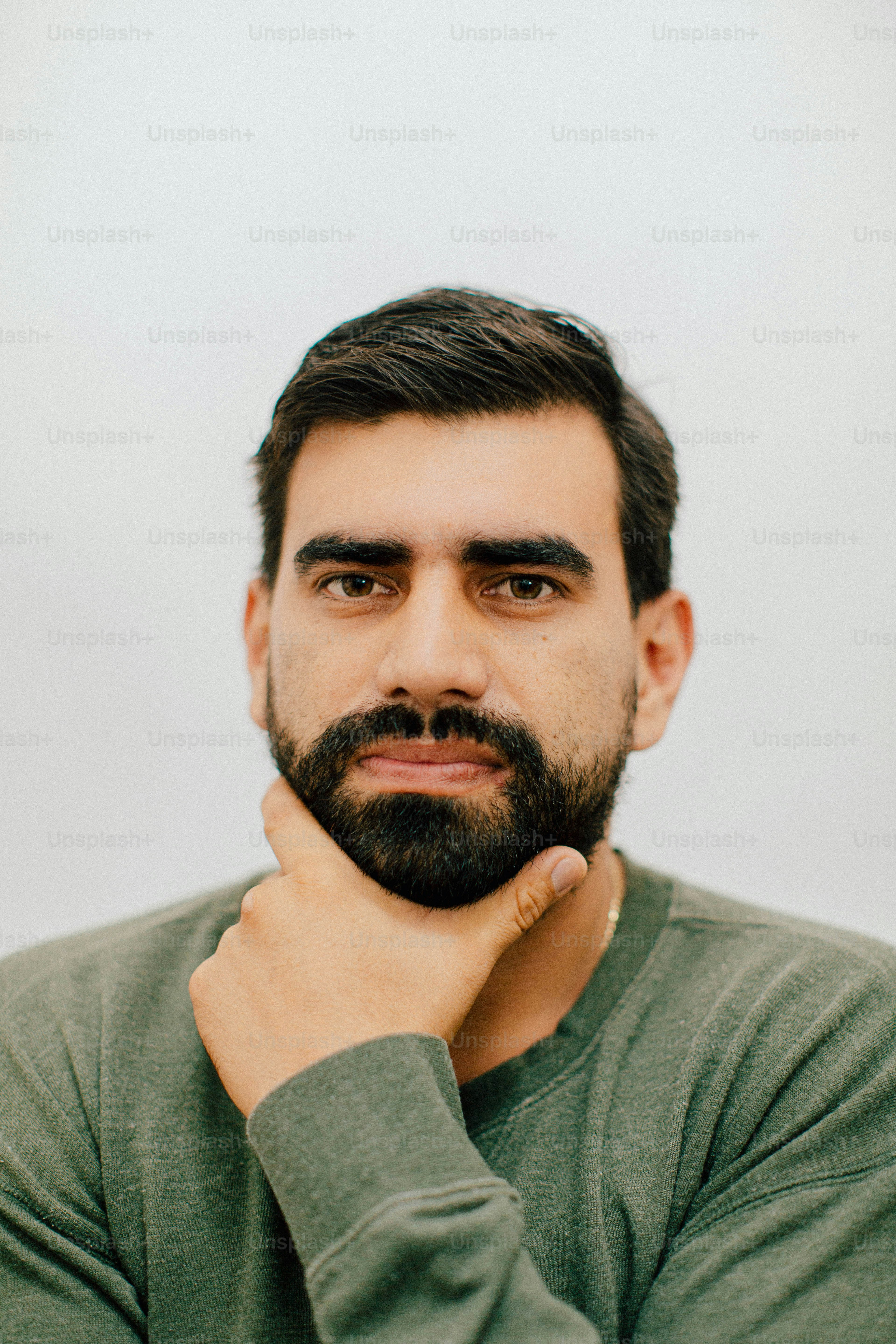 Hombre con barba apoyada en la barbilla en la mano