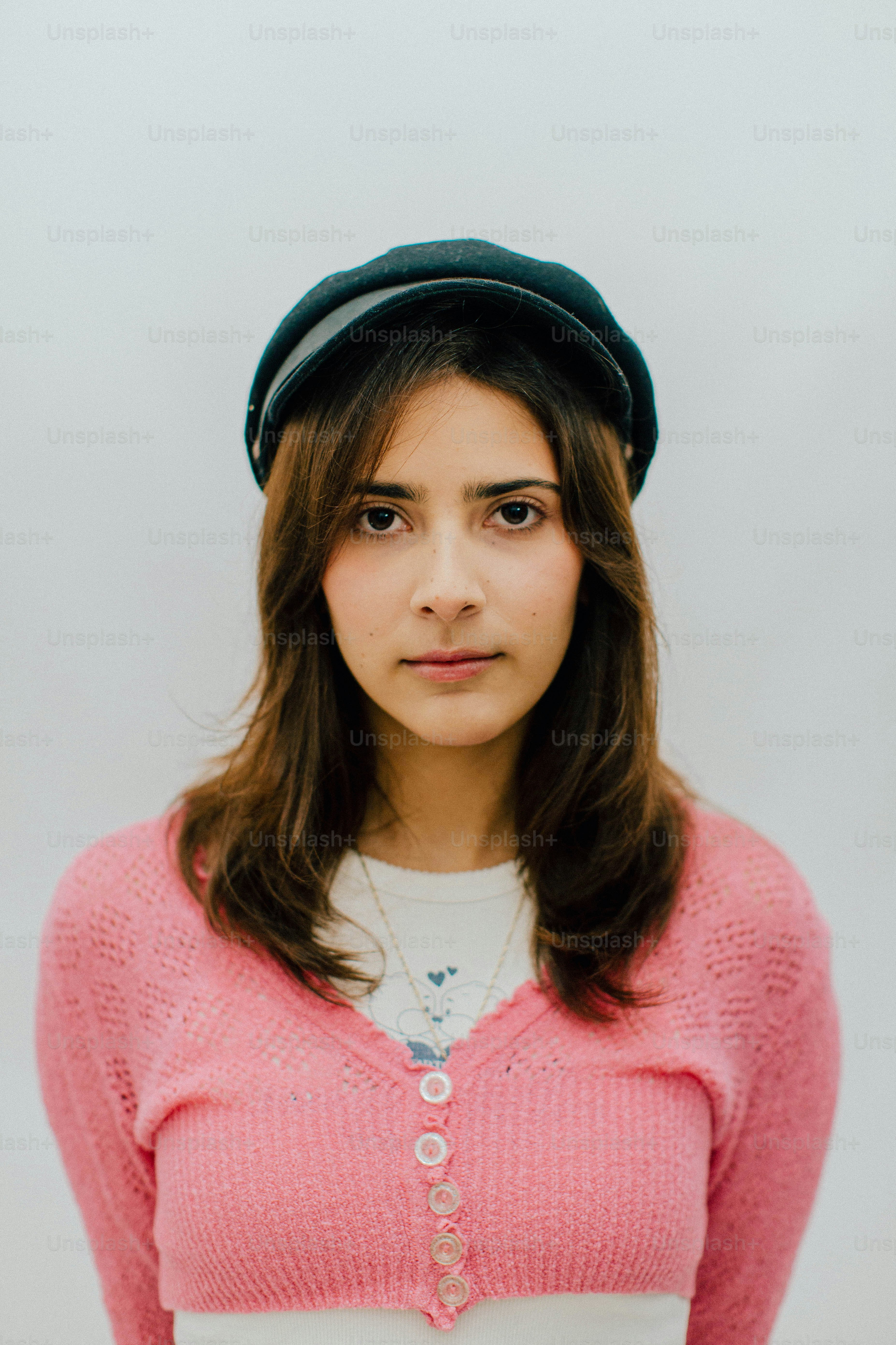 Mujer joven con un cárdigan rosa y una gorra.