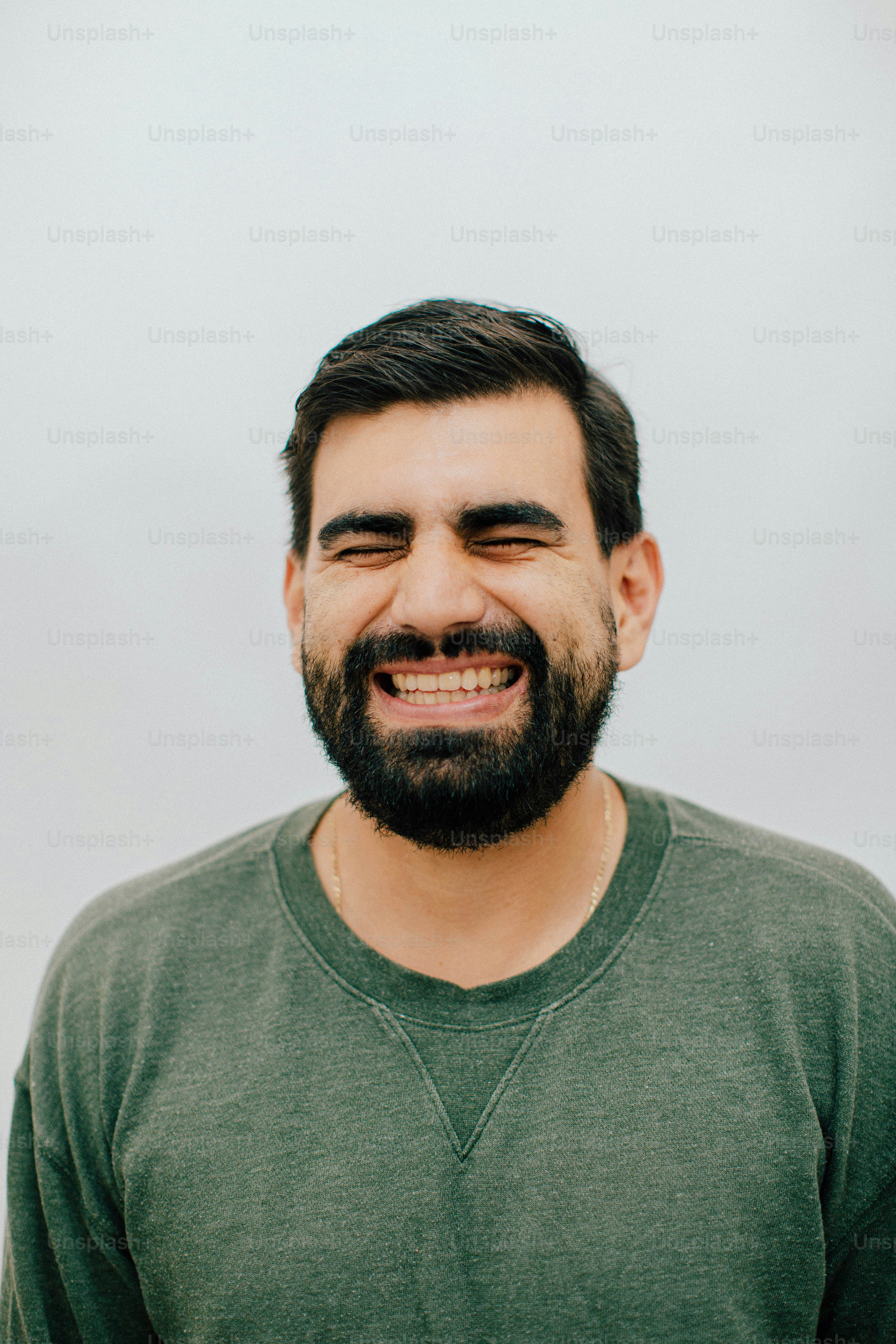 A man with a beard laughing with eyes closed