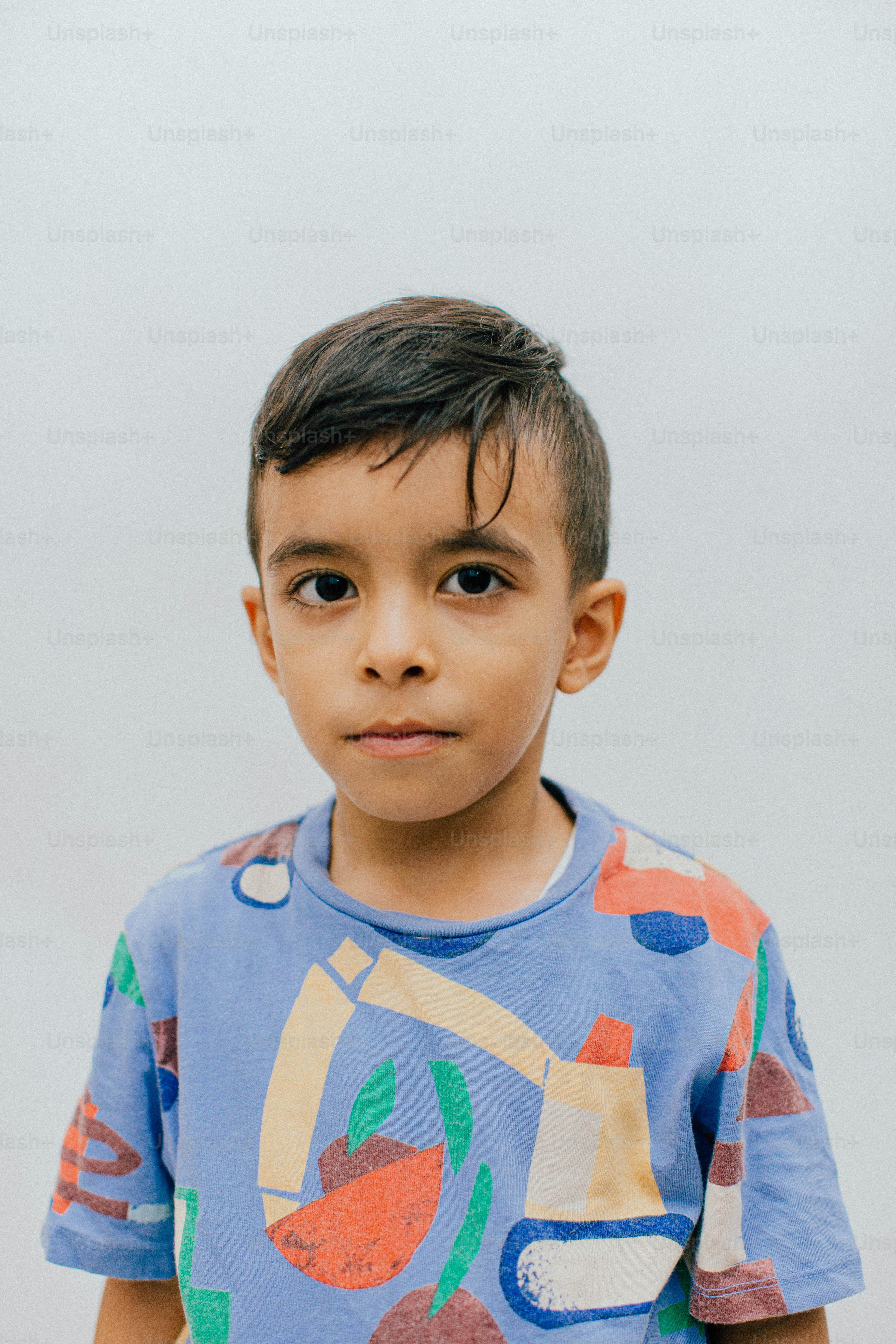 Um menino com cabelo escuro vestindo uma camisa colorida