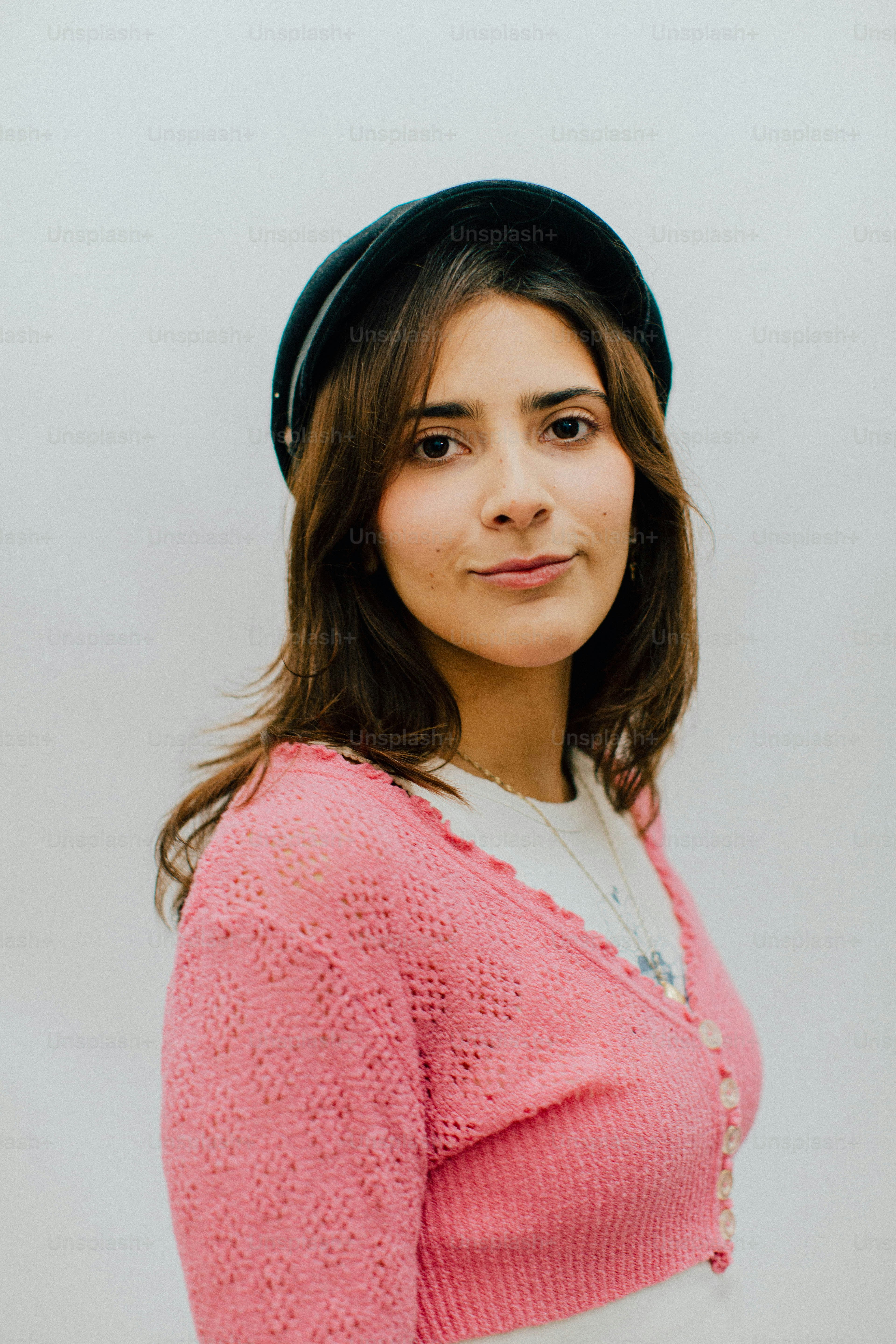 Mujer joven con un cárdigan rosa y un sombrero