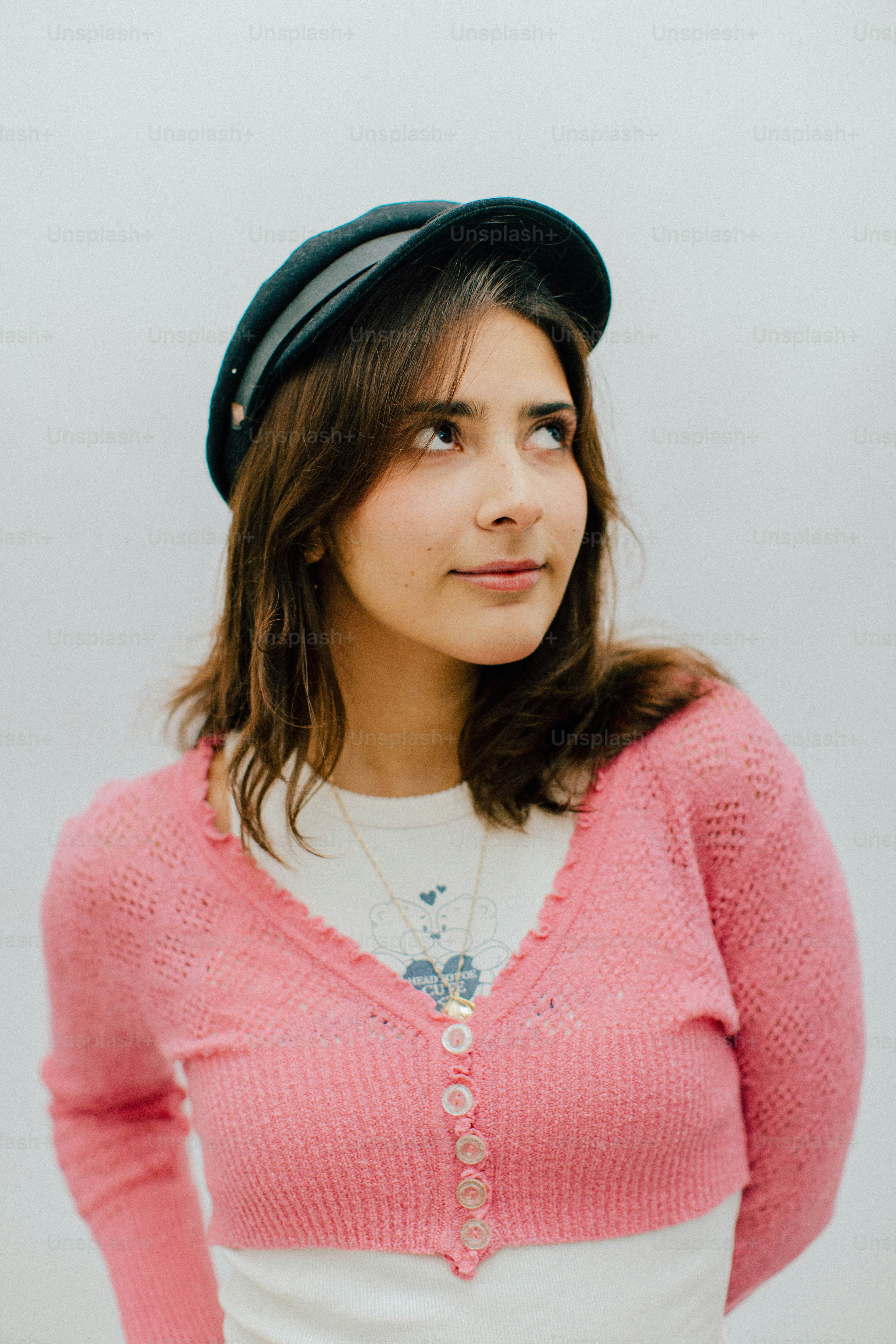 Mujer joven con un cárdigan rosa y un sombrero