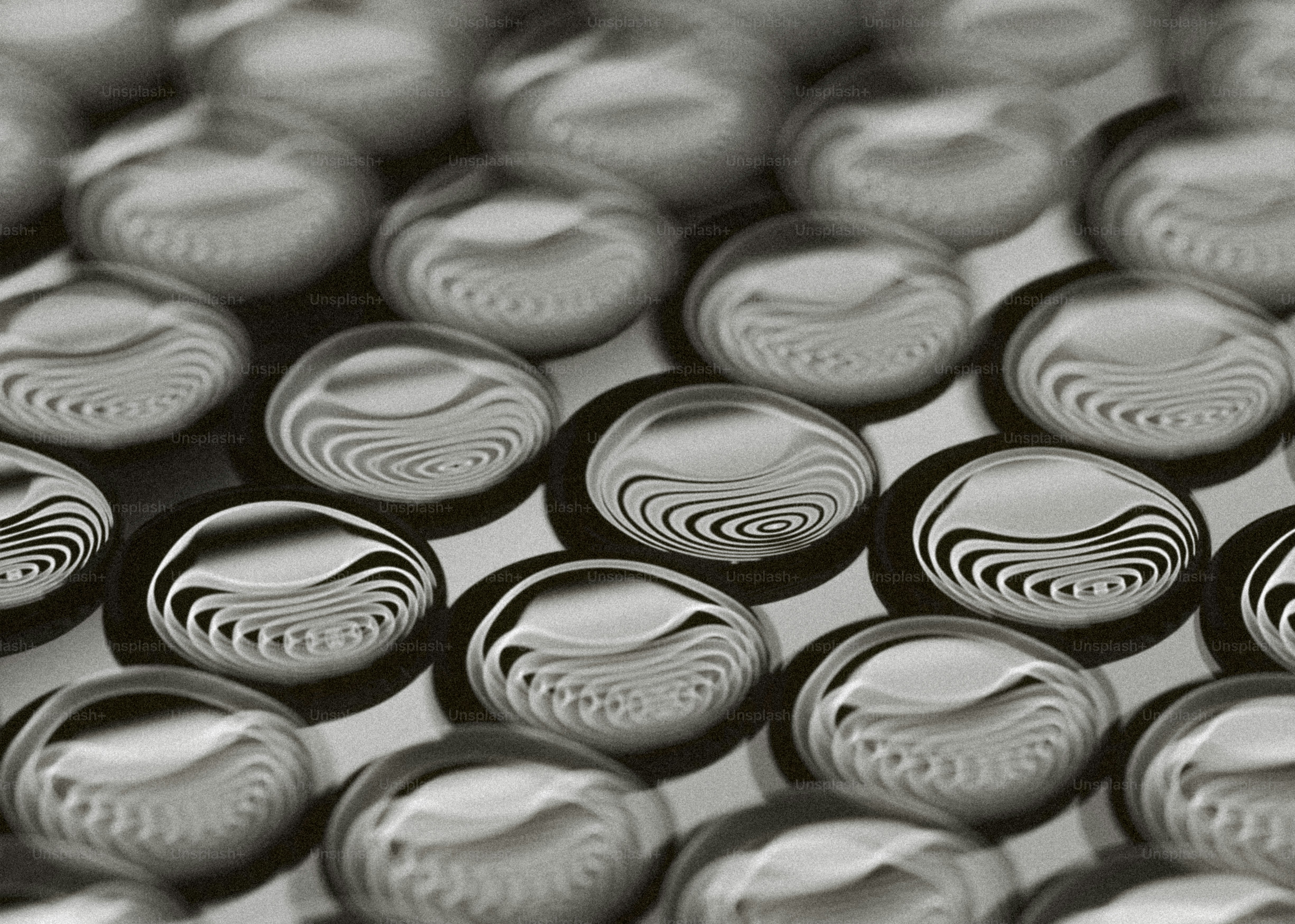 Deretan tetesan bulat reflektif pada permukaan bertekstur.