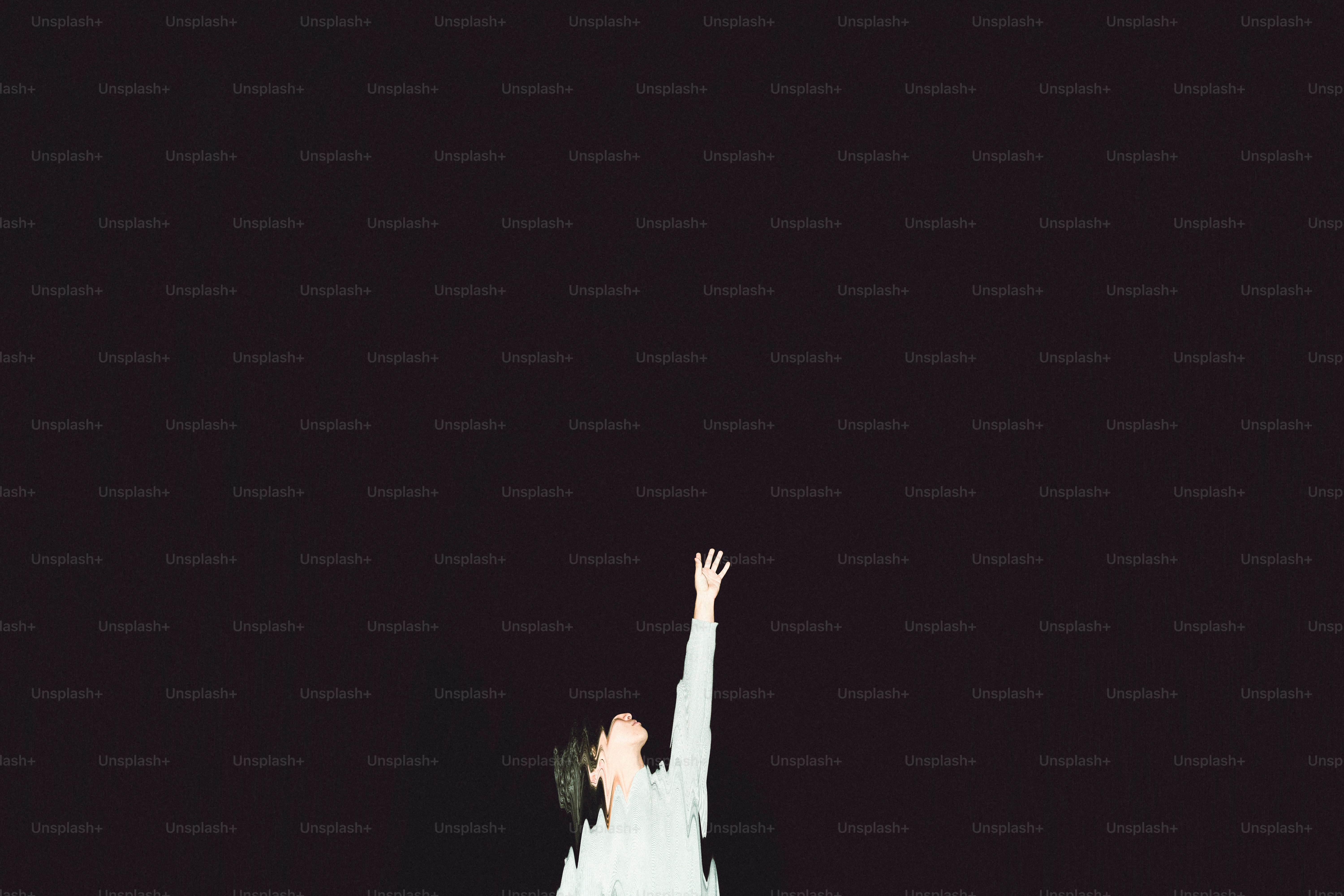 Person reaching up against dark background