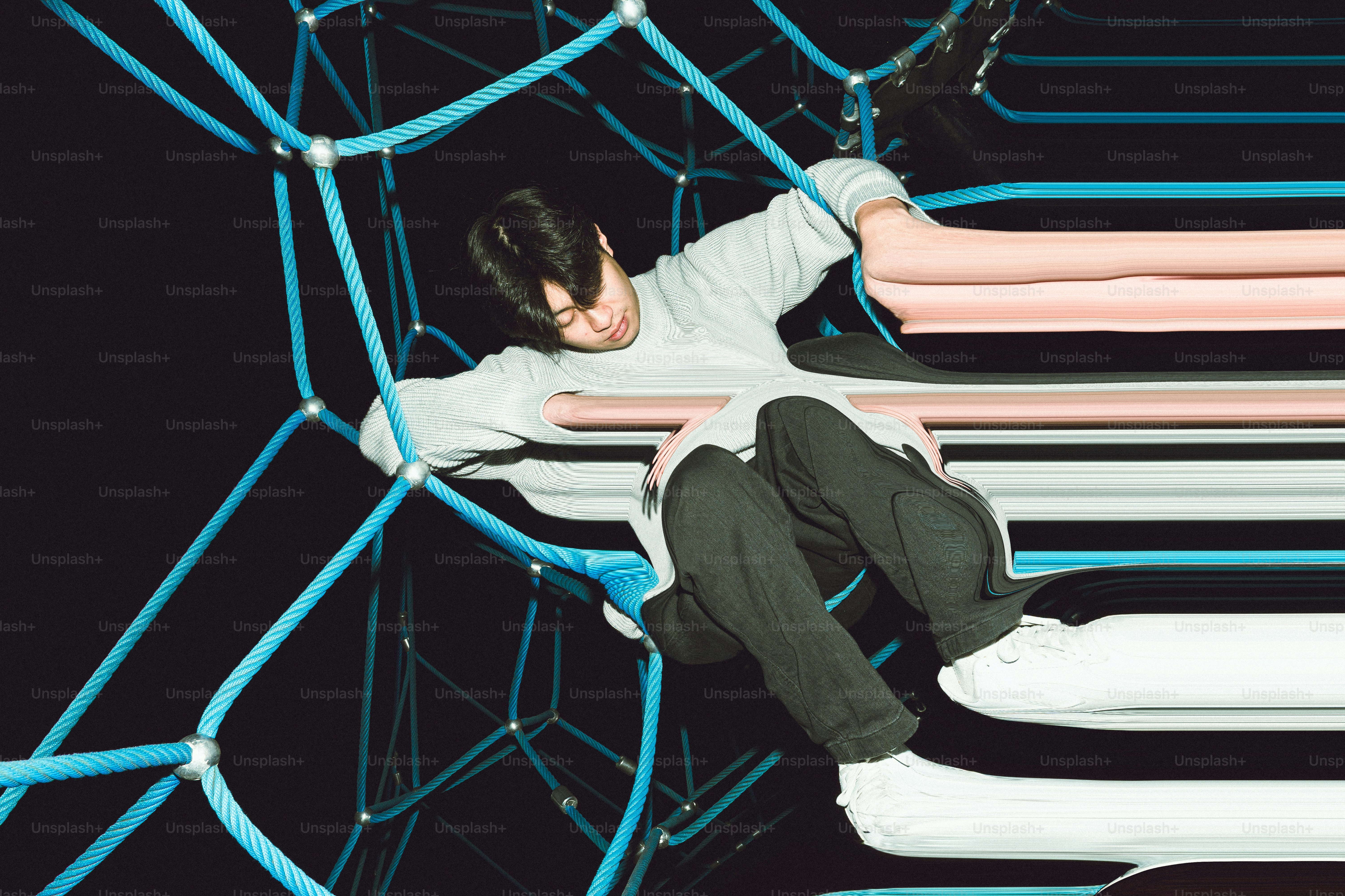 Young man climbing on a blue net structure