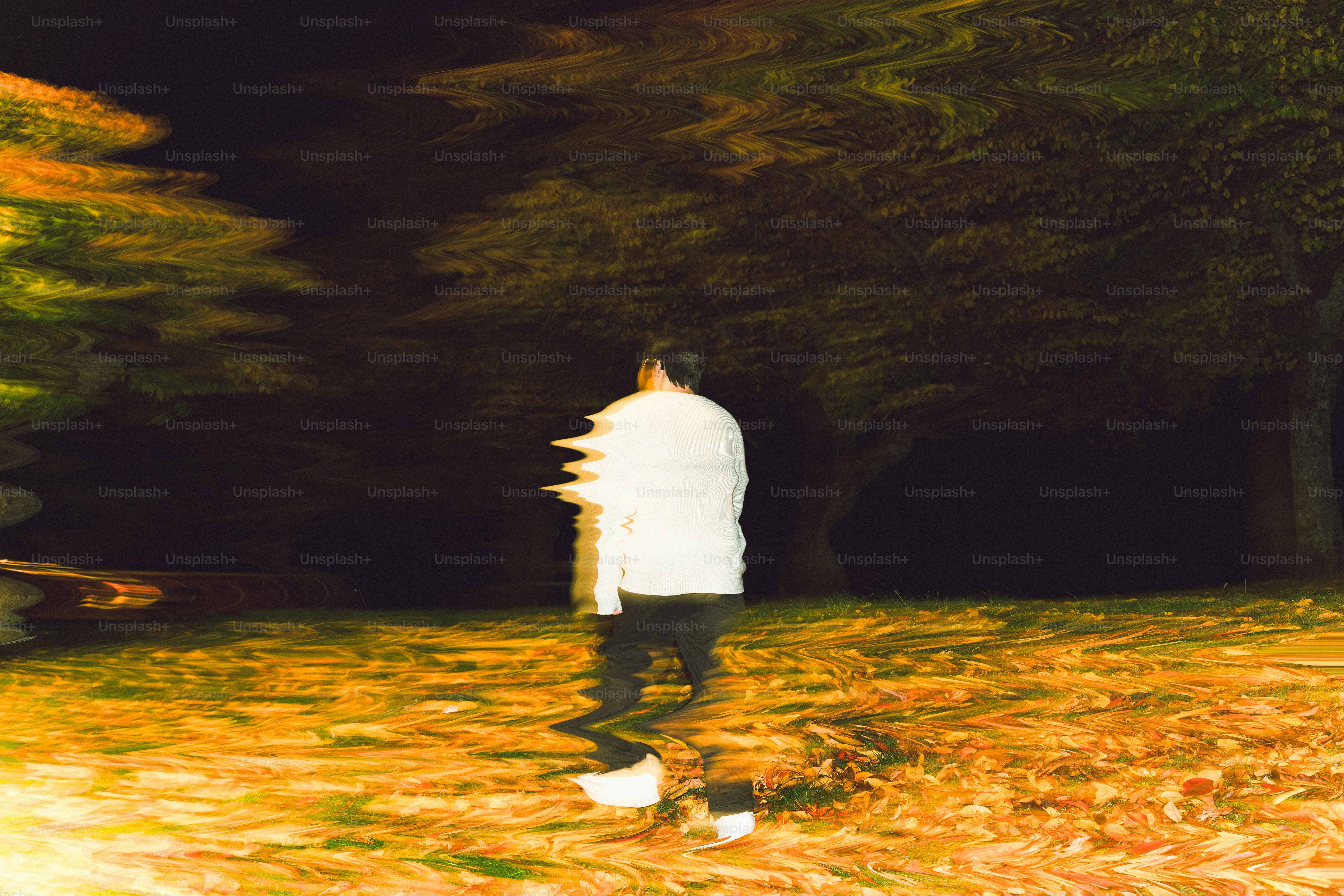 Man walking in a dark, blurry forest at night.