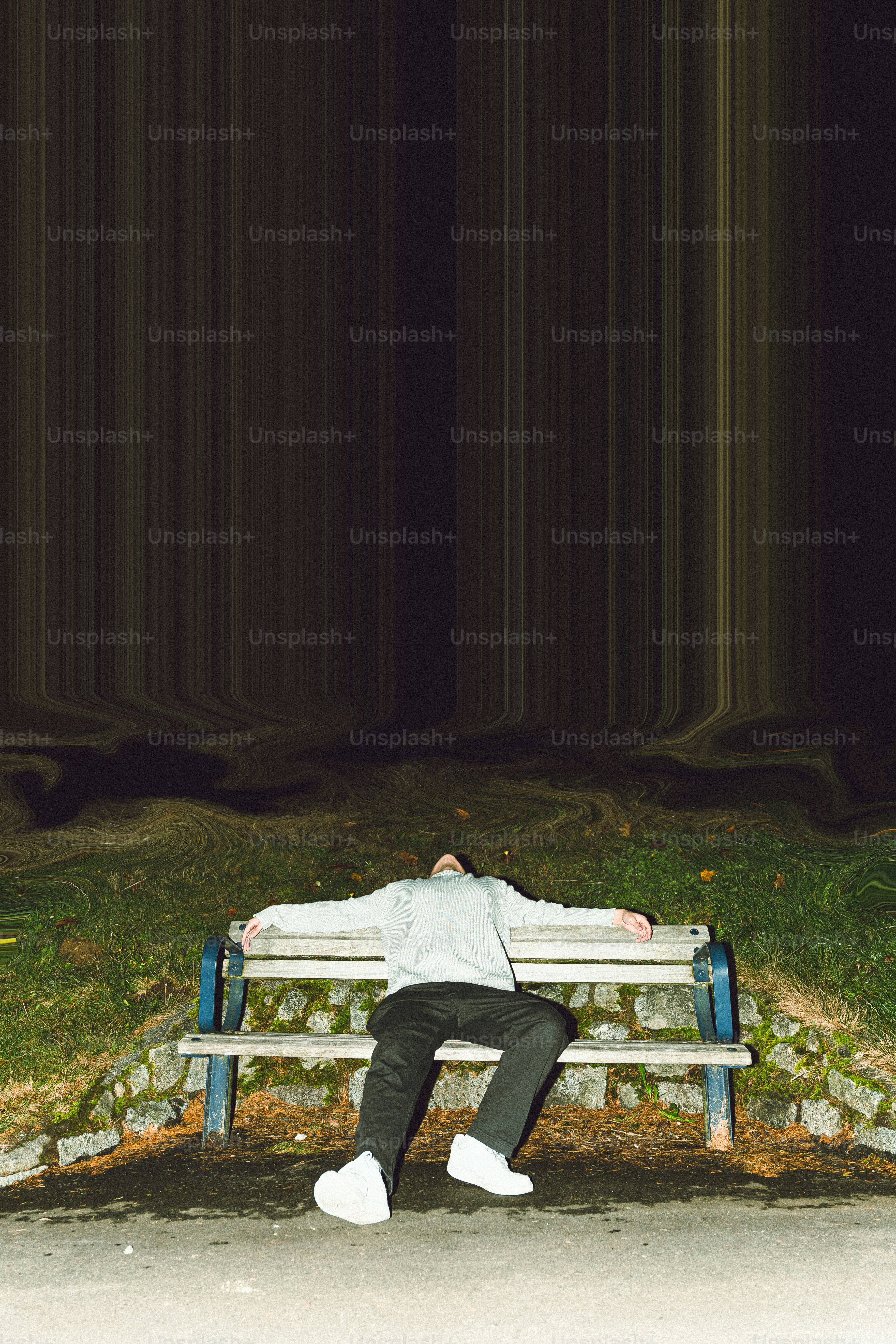Man lying on a park bench at night.