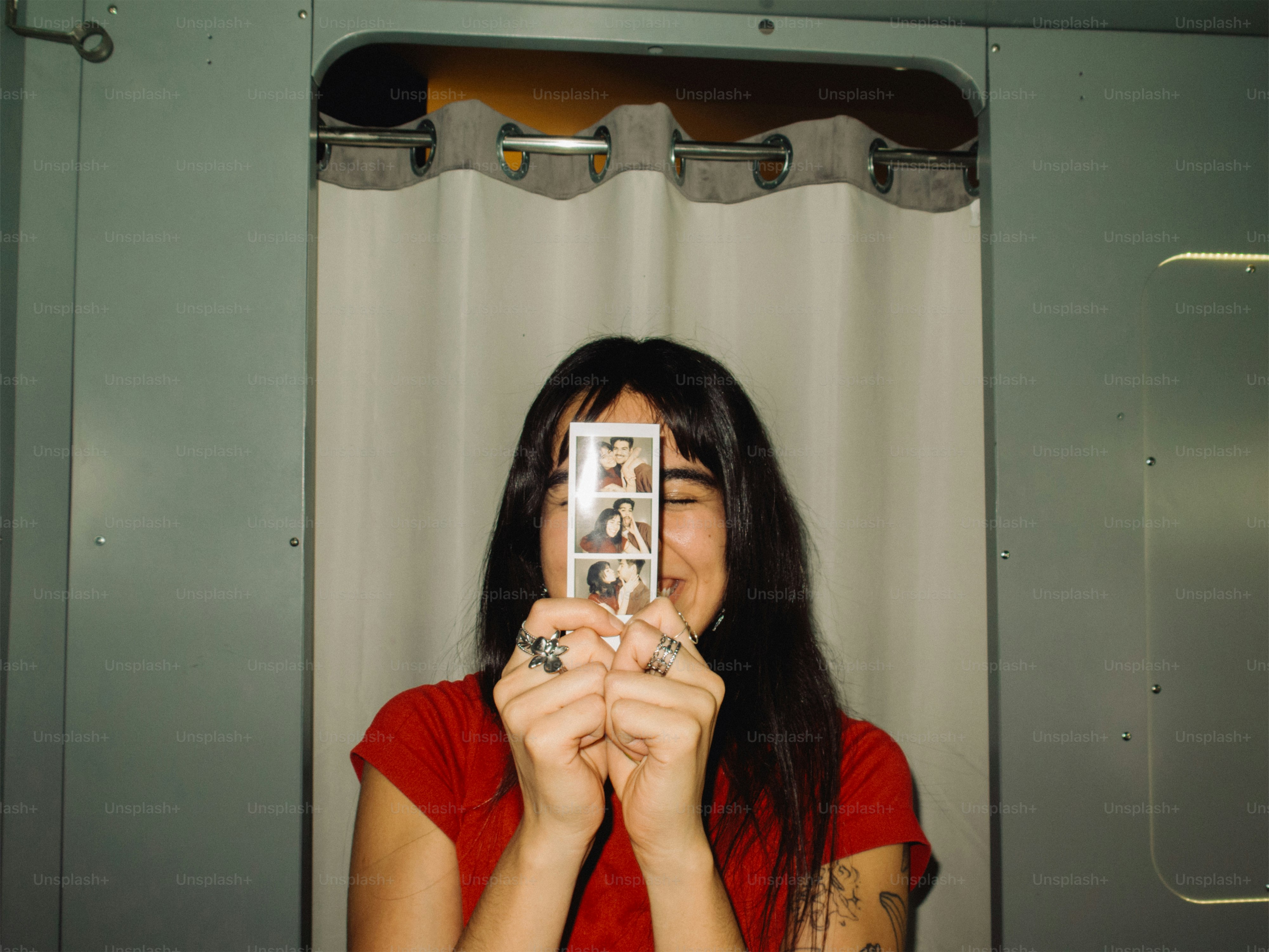 Woman holds up photo booth strip in front of face