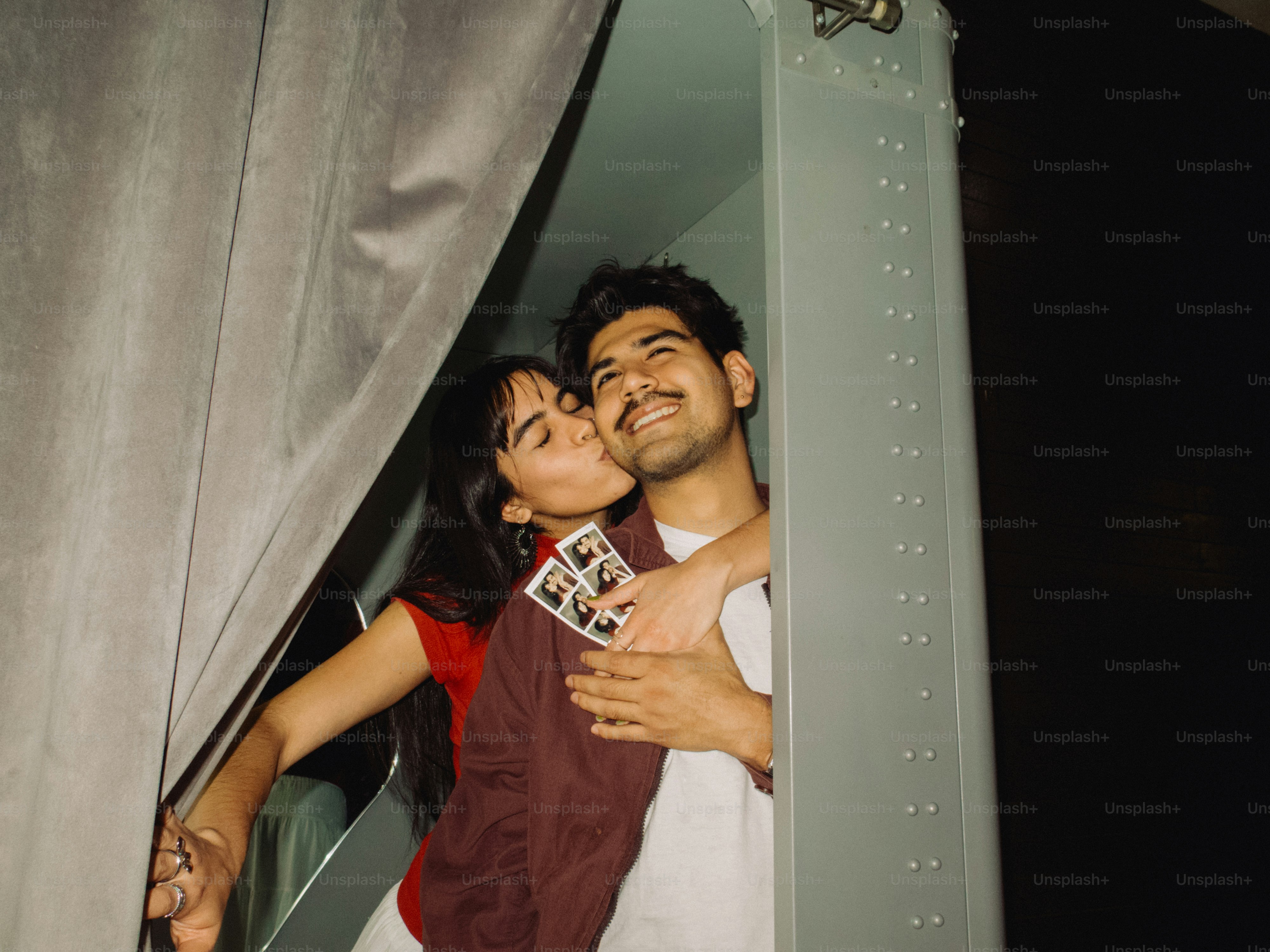 Woman kissing man holding instant photos