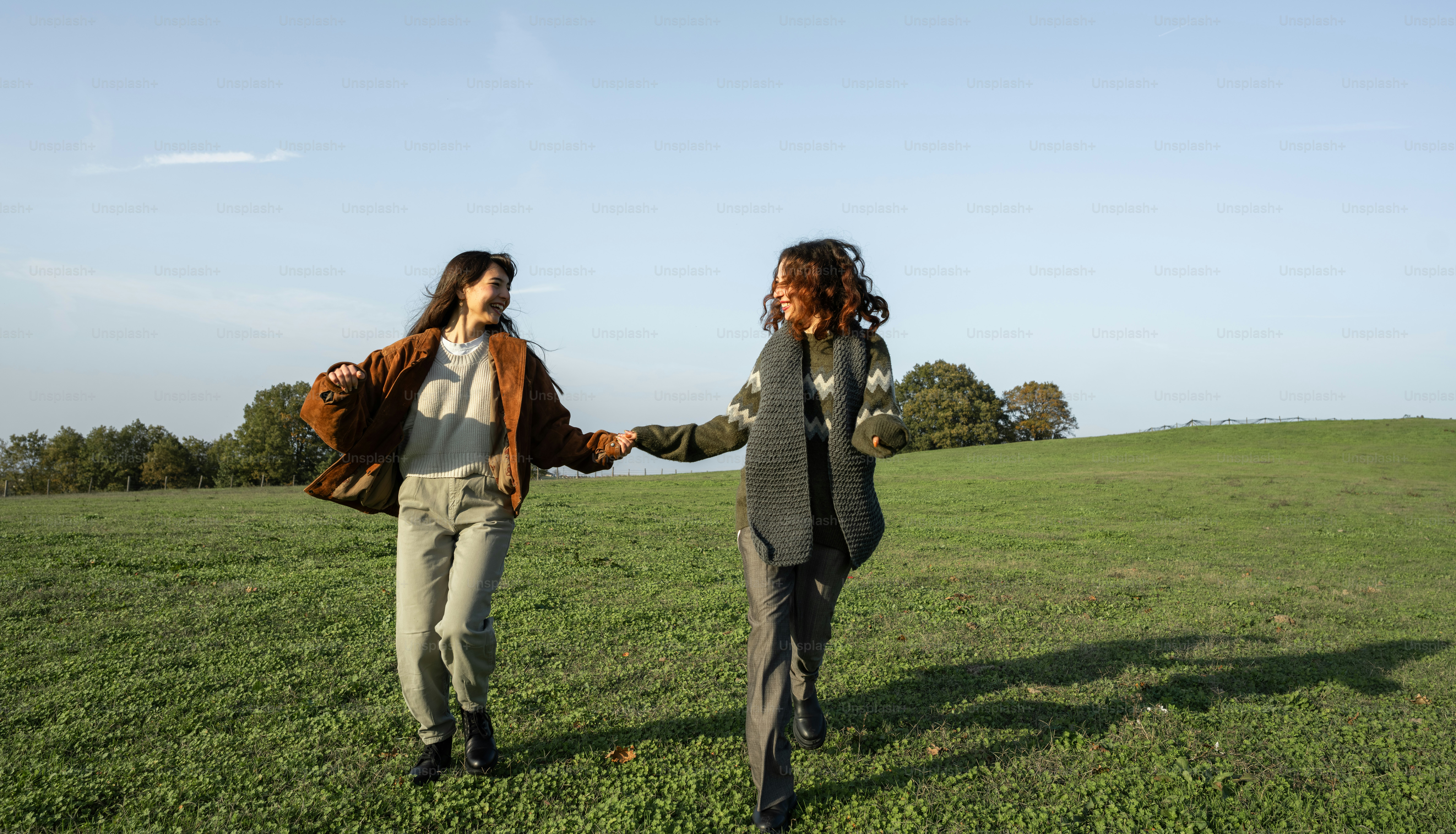 Two women holding hands running in a grassy field photo – Autumn Image ...