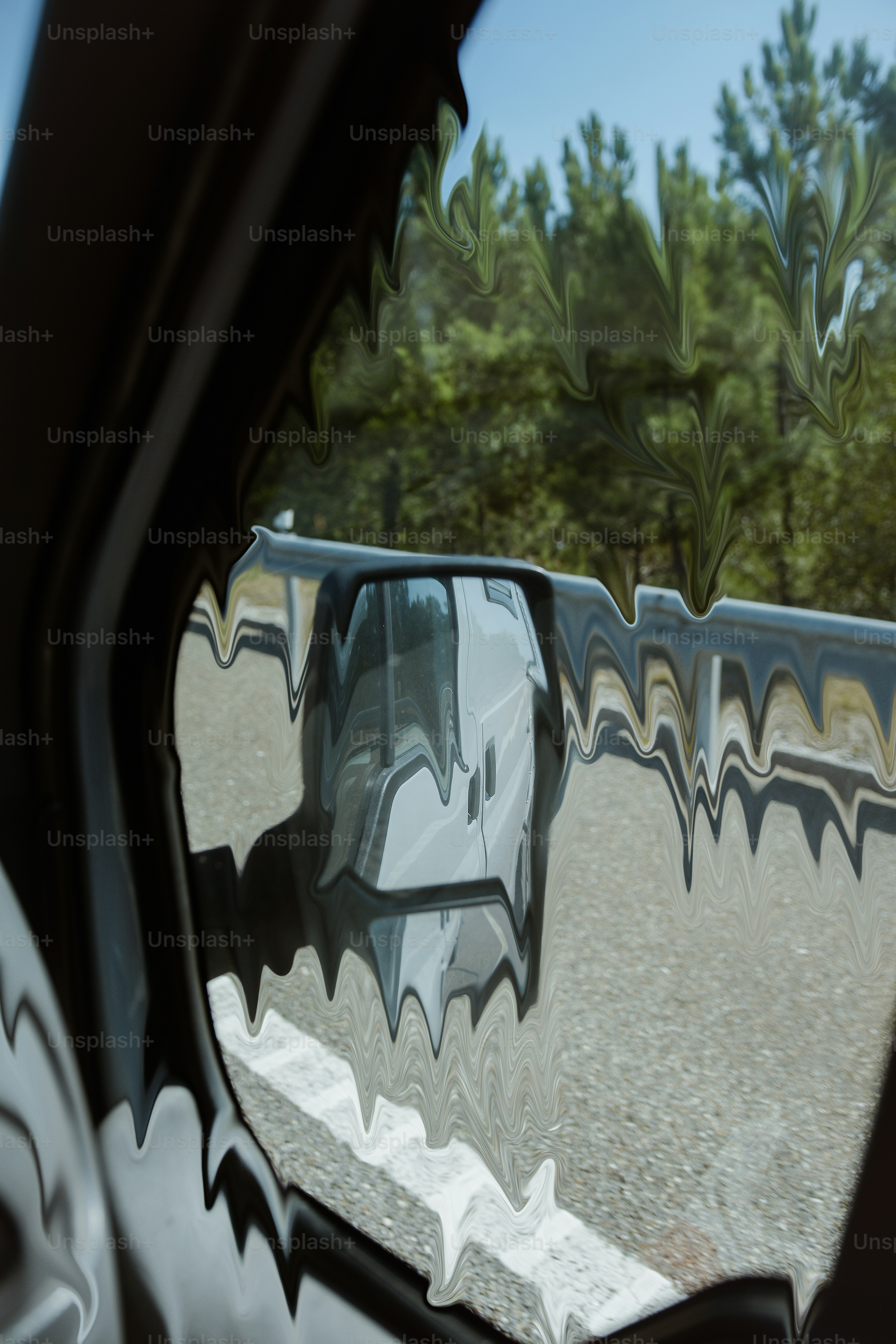 Car side mirror reflecting a white van on a road.