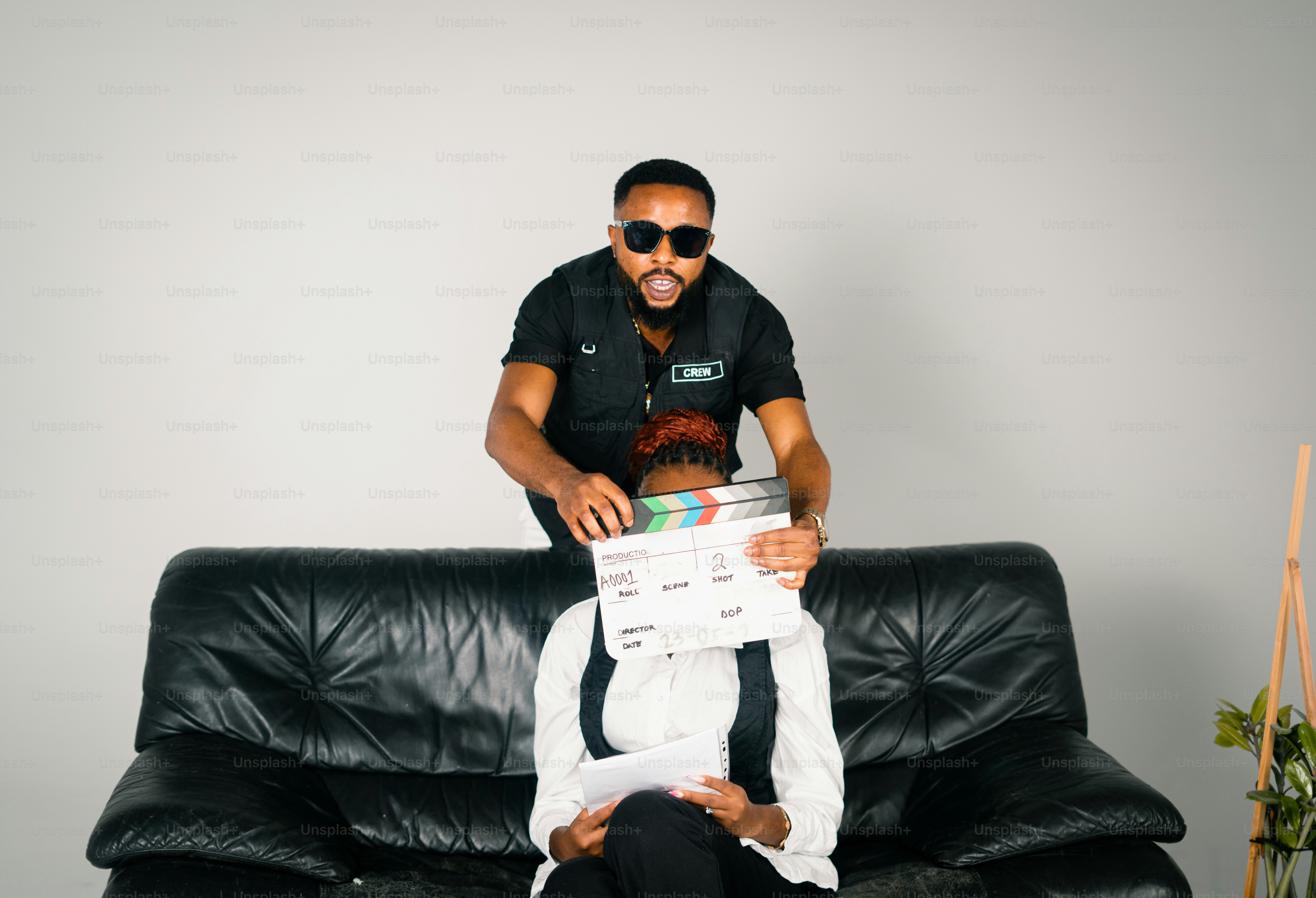 Man with sunglasses holds clapperboard over woman