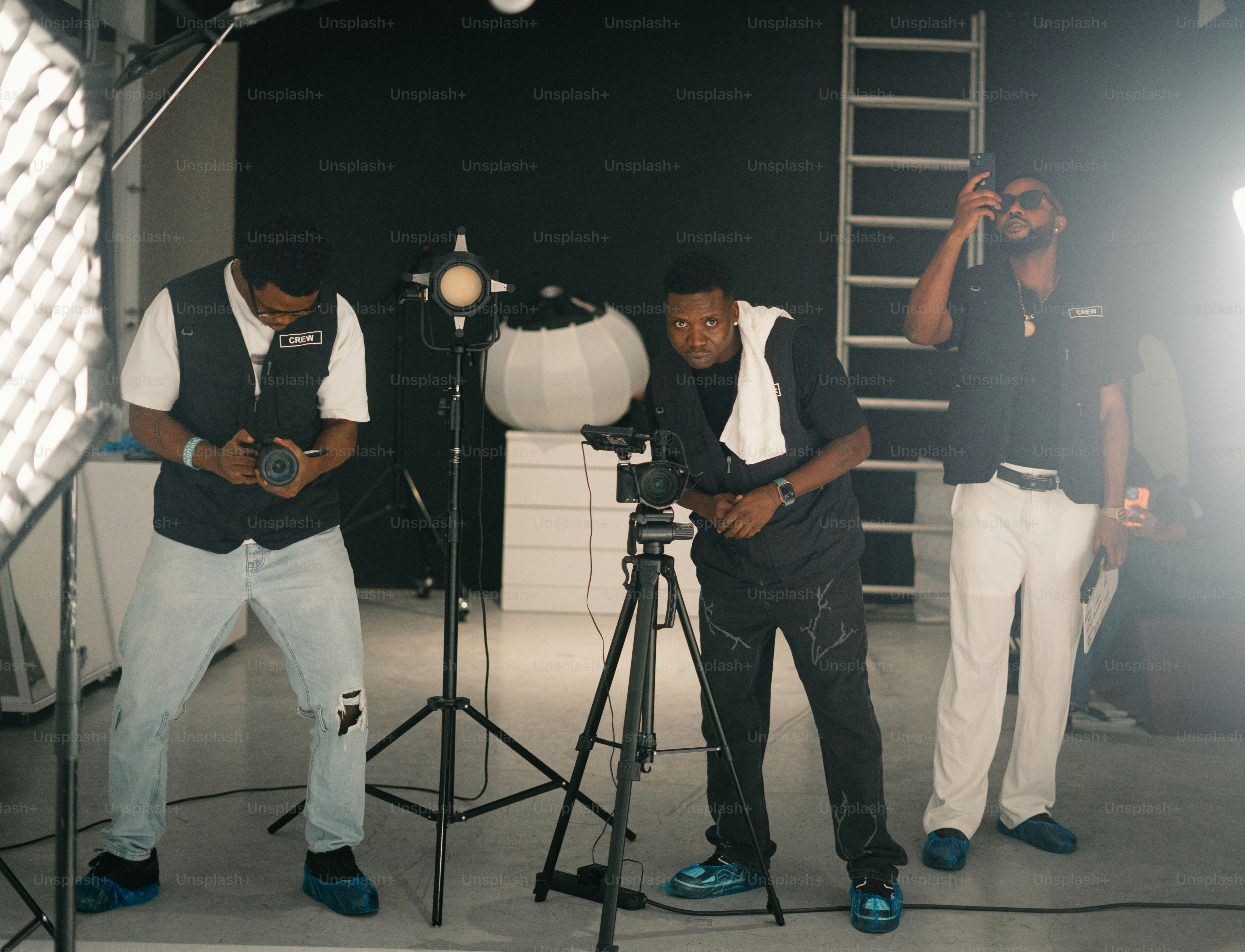 Three men operating camera equipment in a studio.