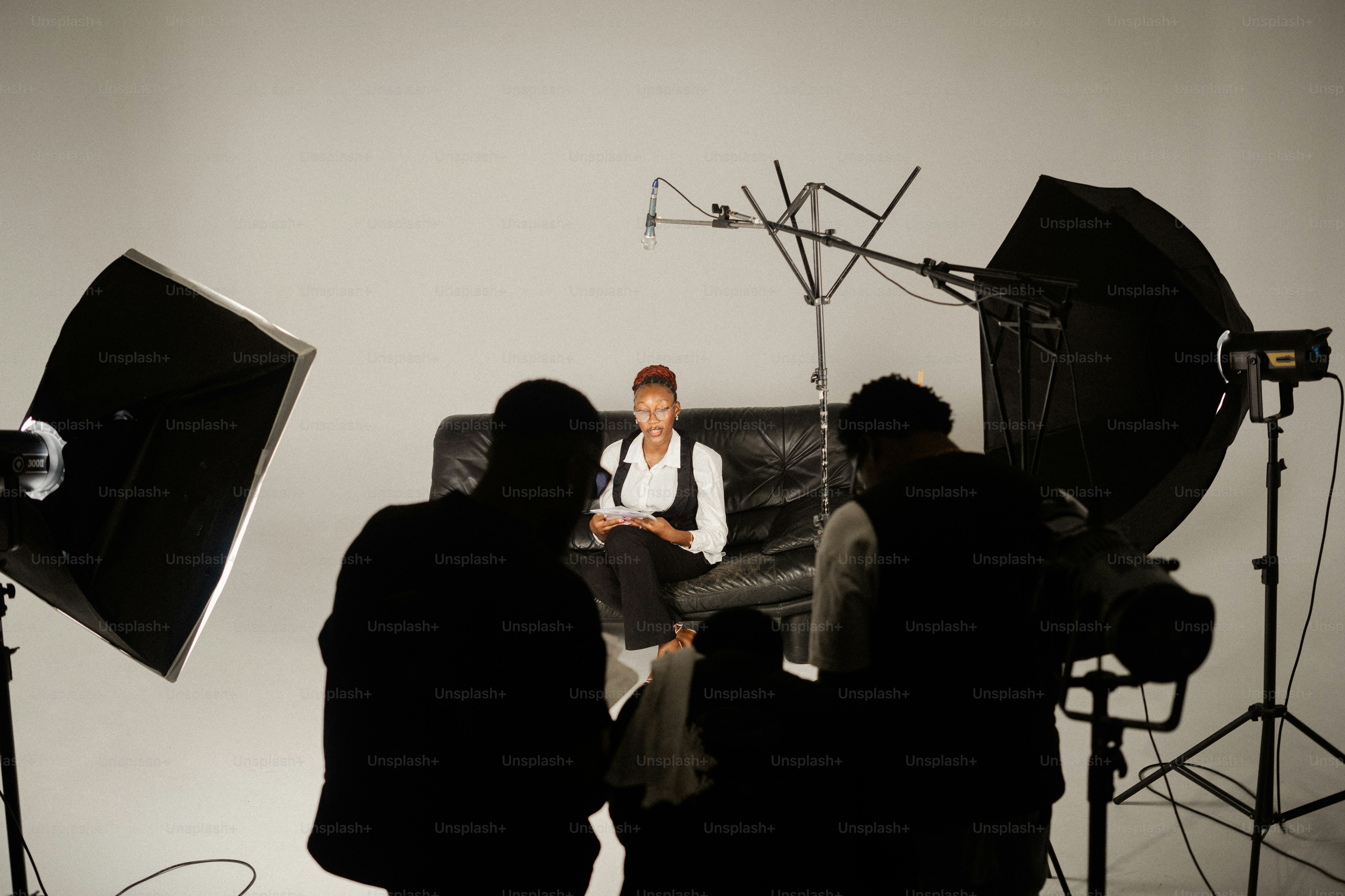 Filming crew works with woman on a couch.