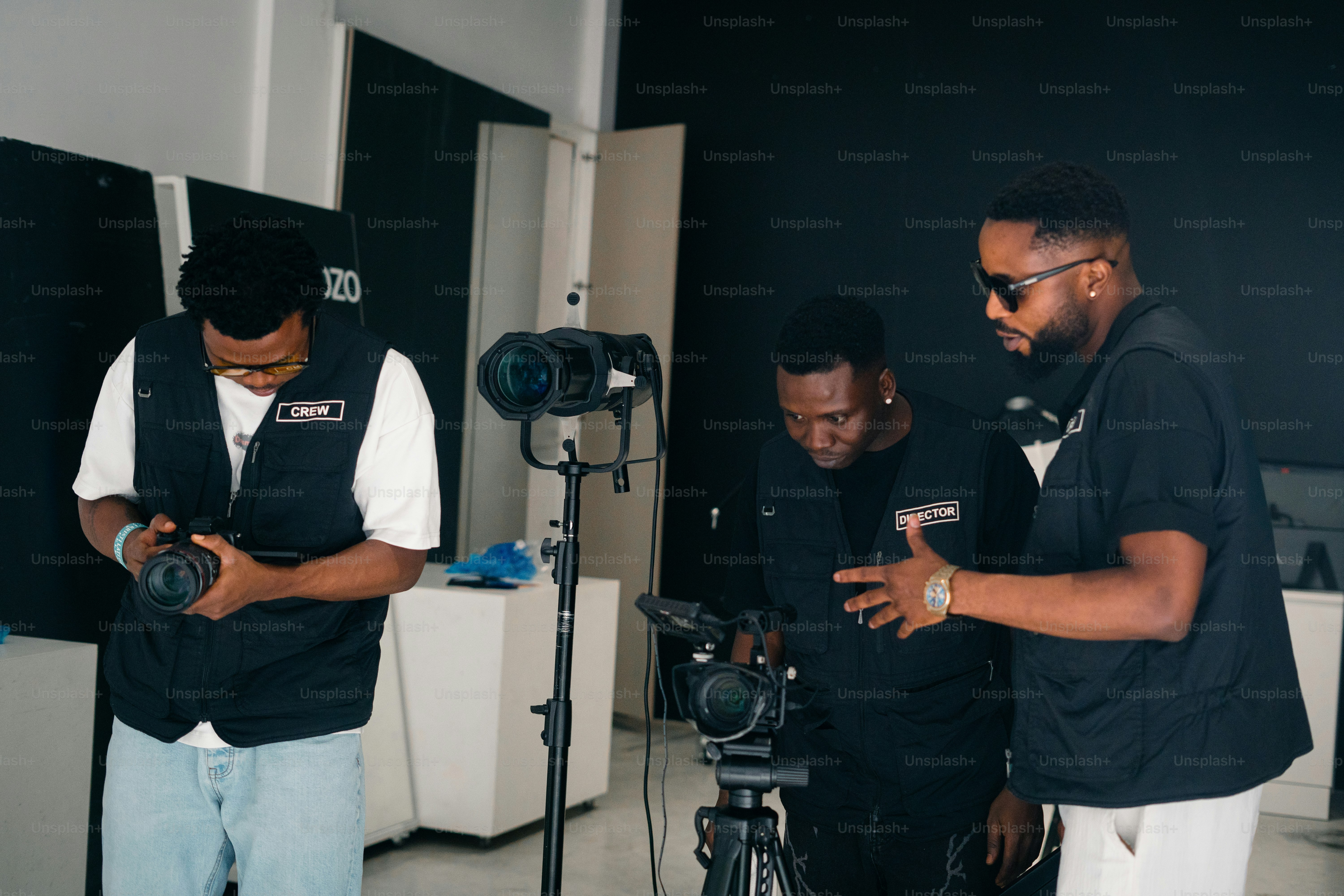 Three men working with camera equipment in studio.