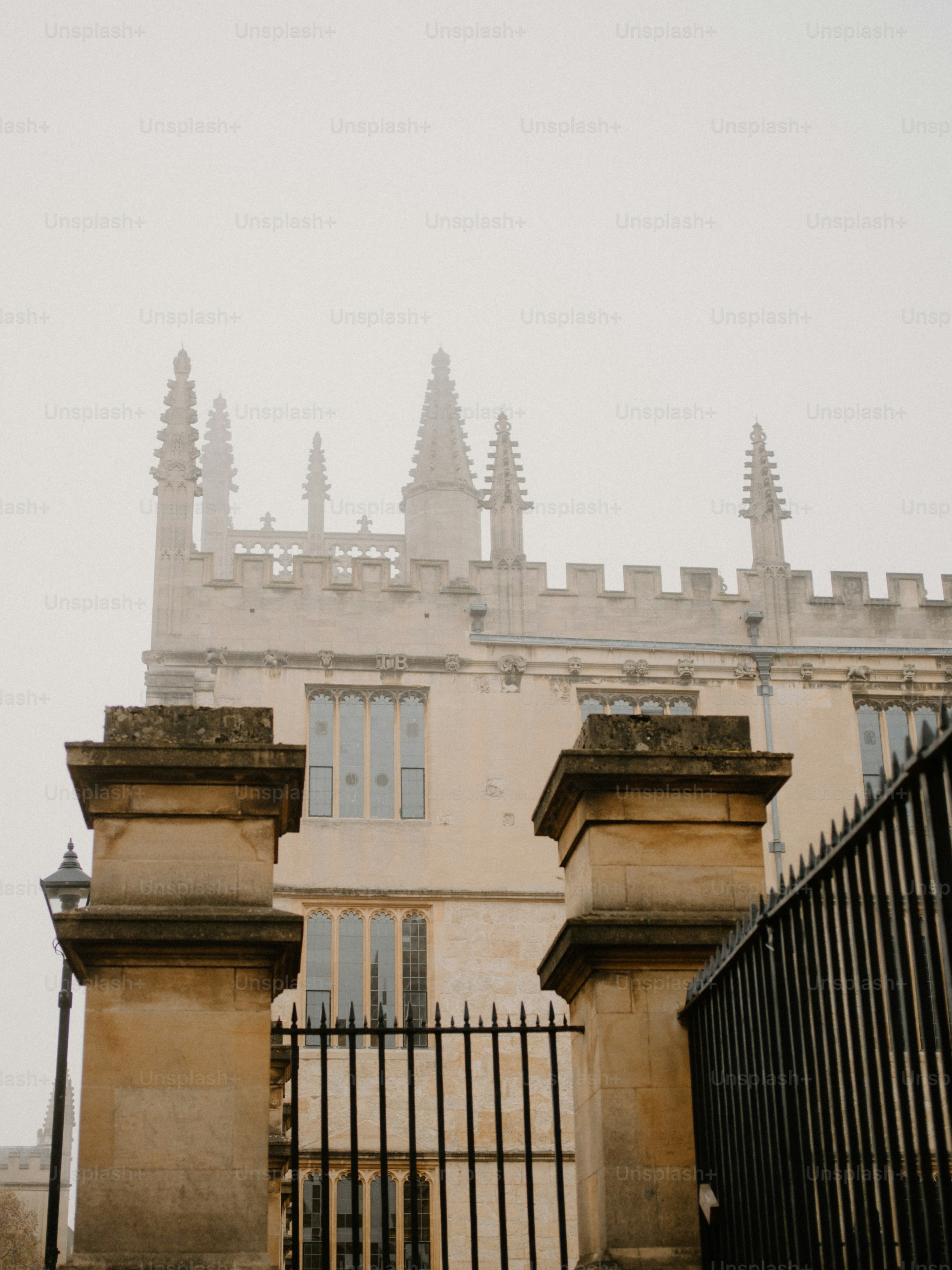 Historic building facade behind stone pillars and fence.