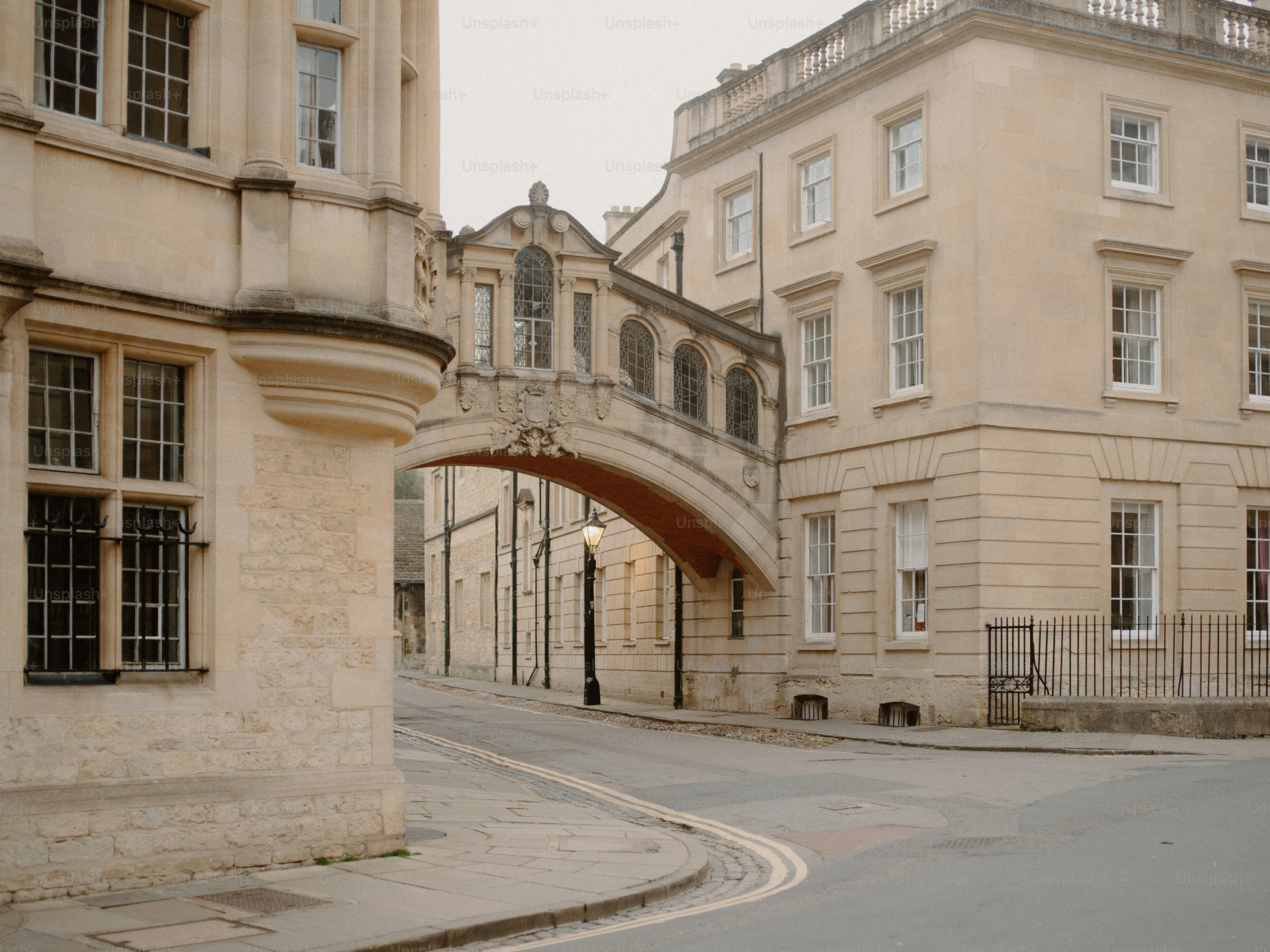 An arched bridge connects two historic stone buildings.