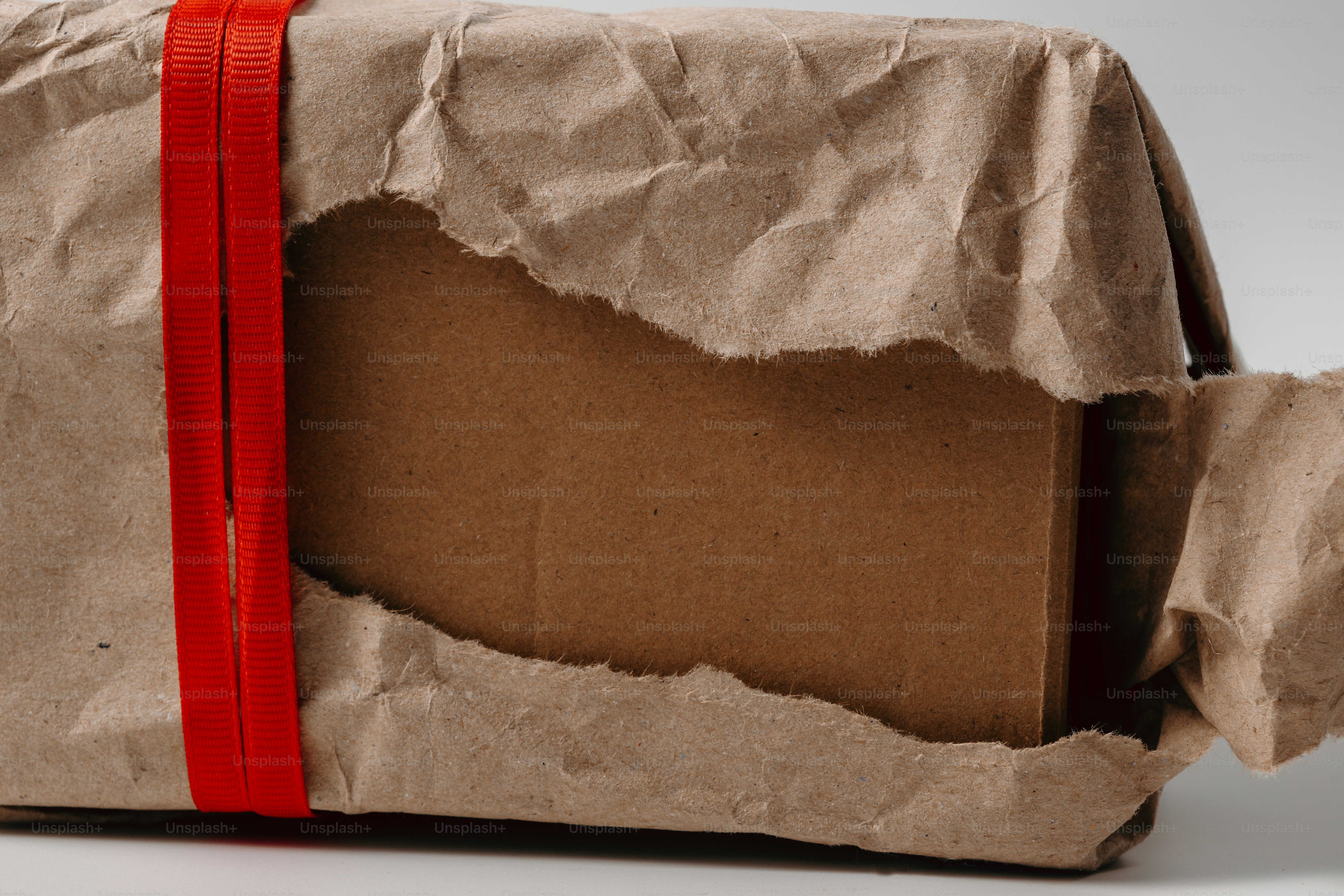 Brown box wrapped in crinkled paper and red ribbon