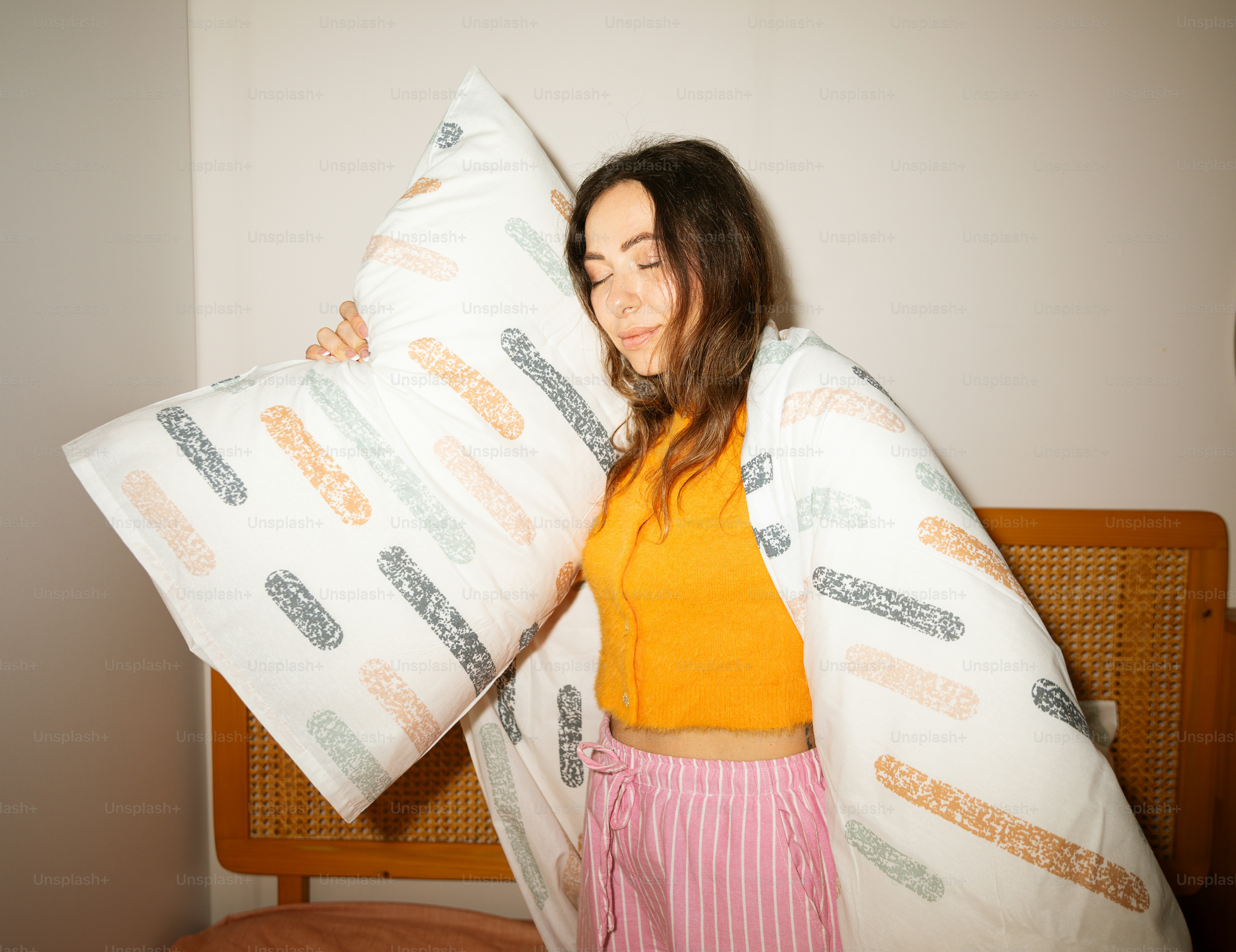 Jeune femme tenant un oreiller sous une couverture