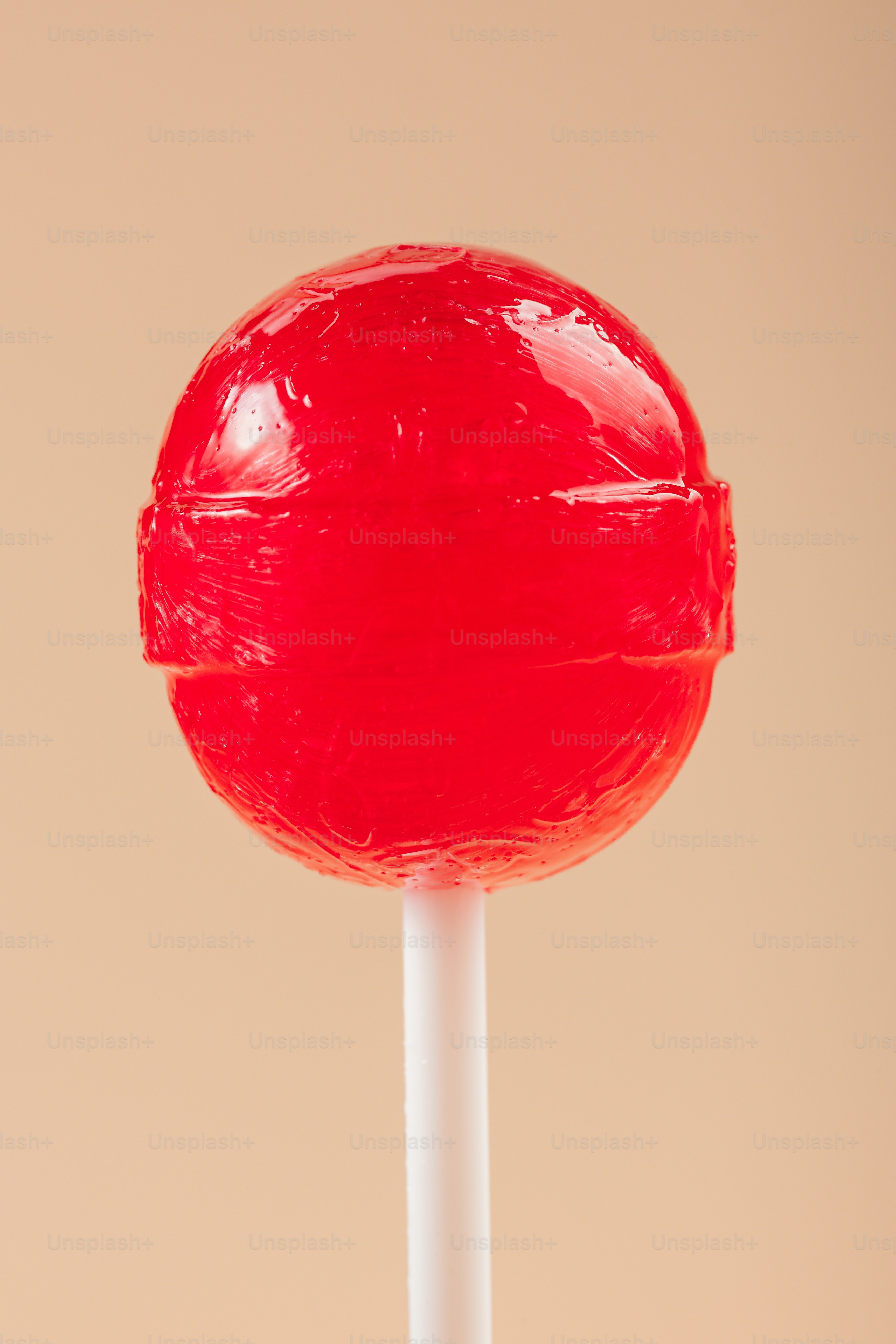 A single red lollipop on a white stick.