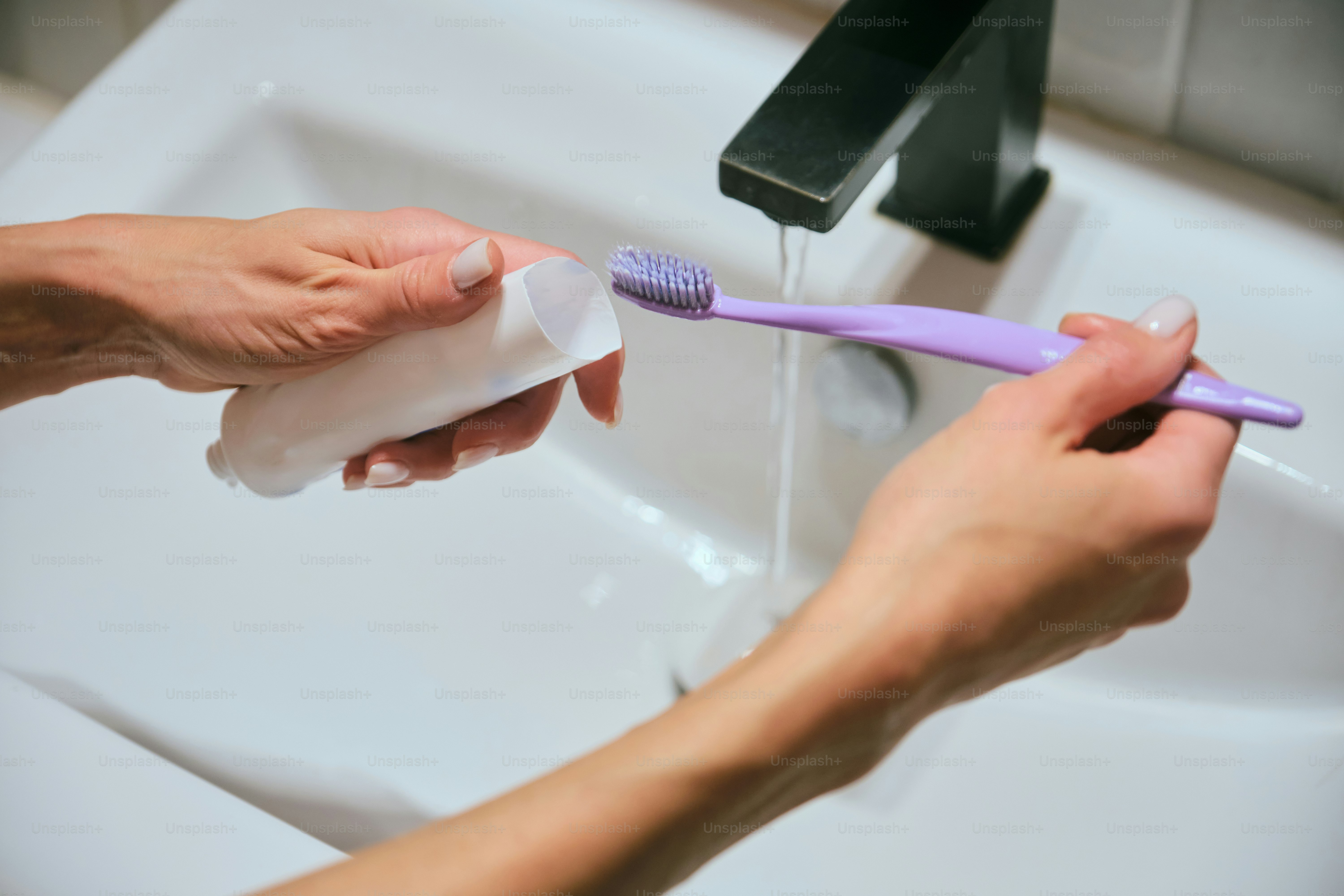 Hände, die eine Zahnbürste unter einem Wasserhahn spülen.