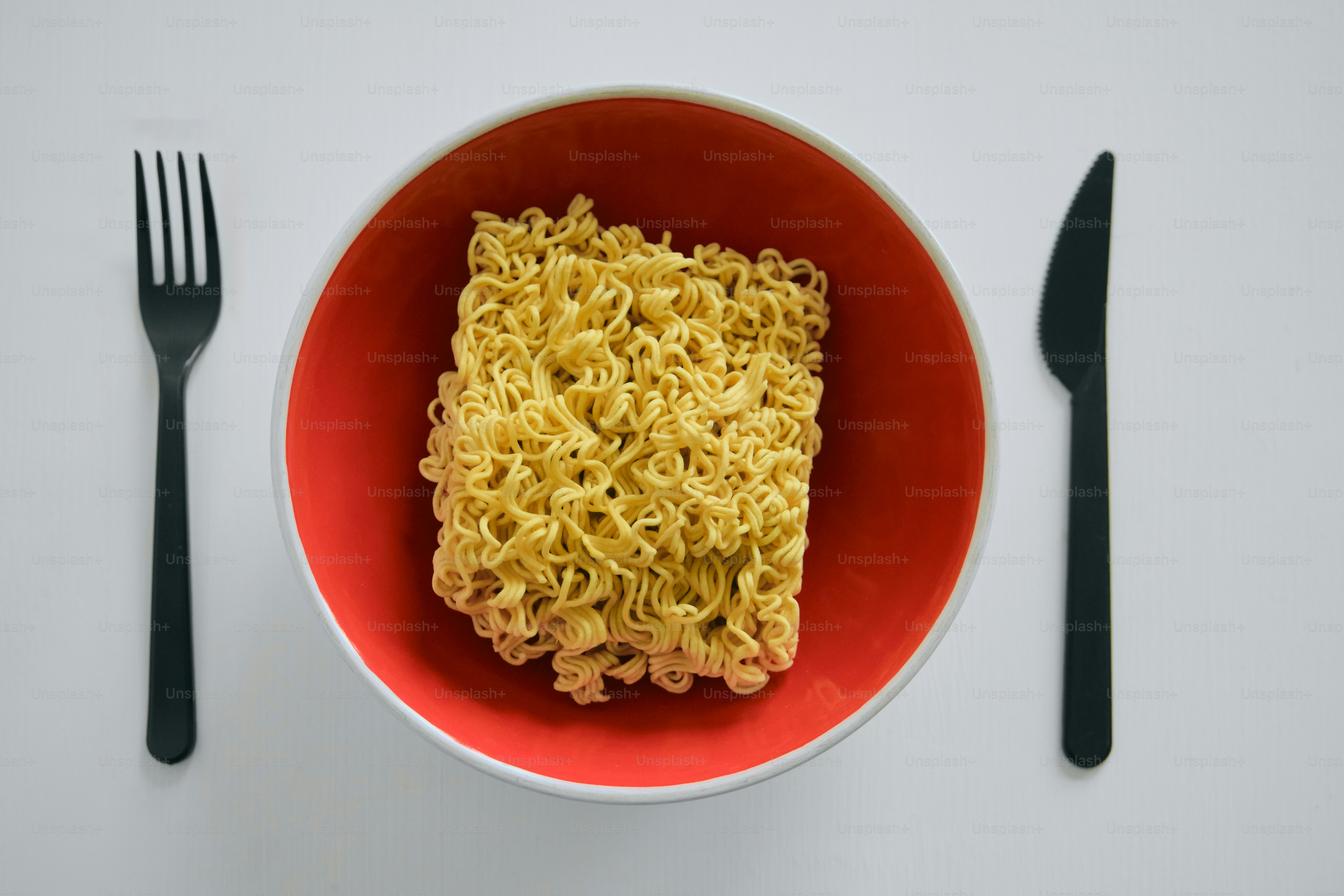 A block of instant noodles in a red bowl.