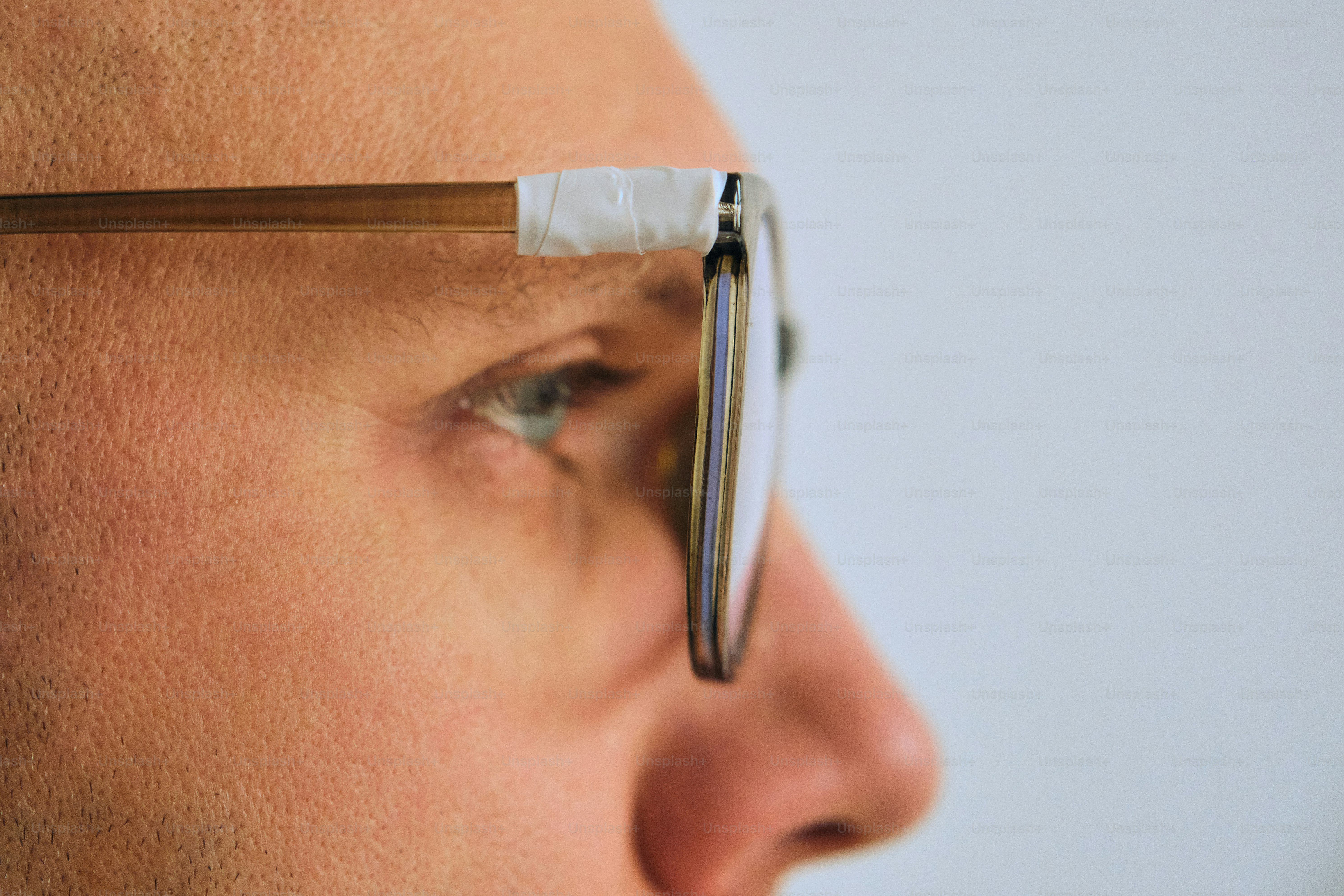 Die Brille des Mannes wird mit Klebeband am Bügel repariert.