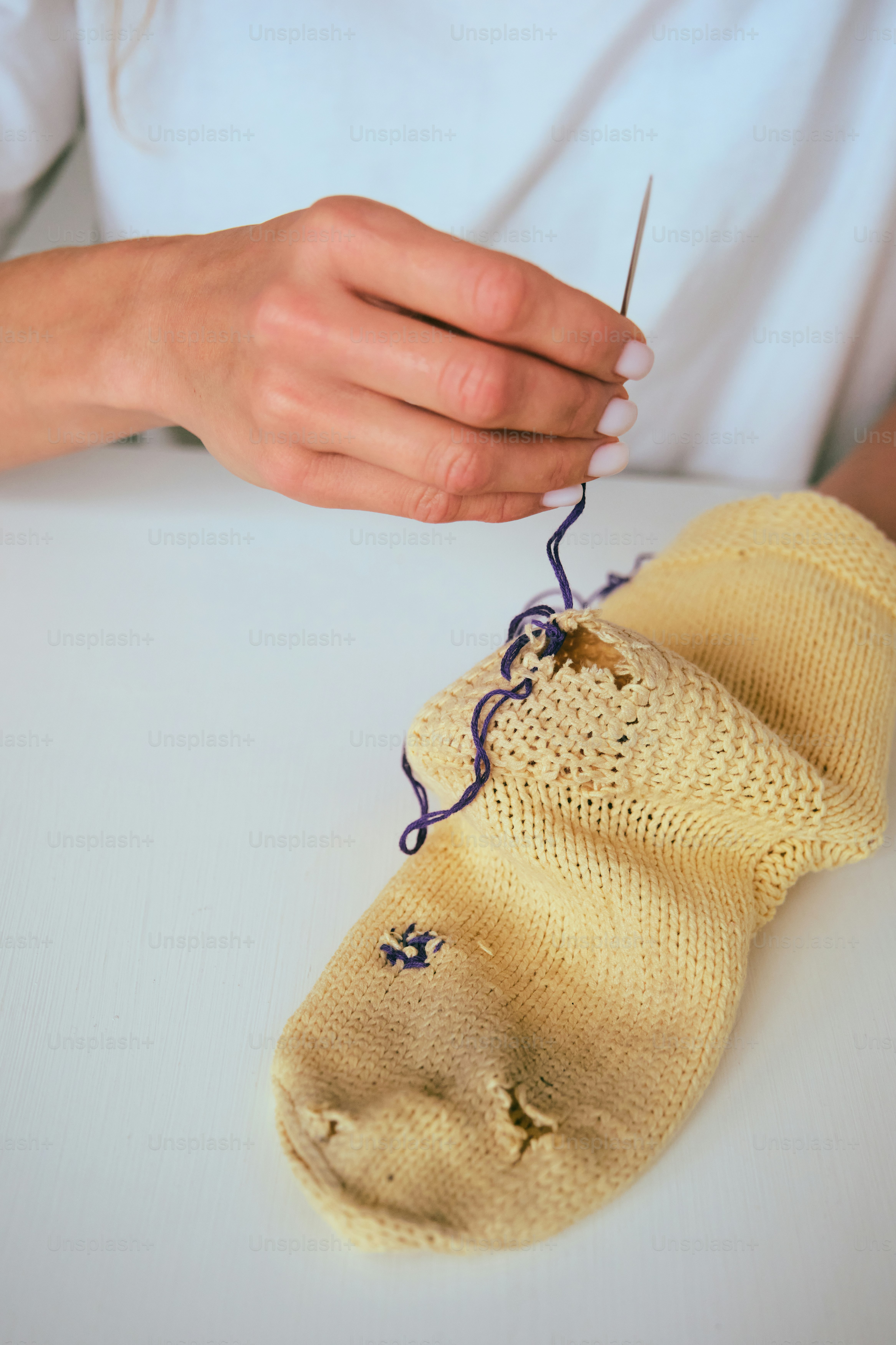 Woman mending a hole in a yellow sock